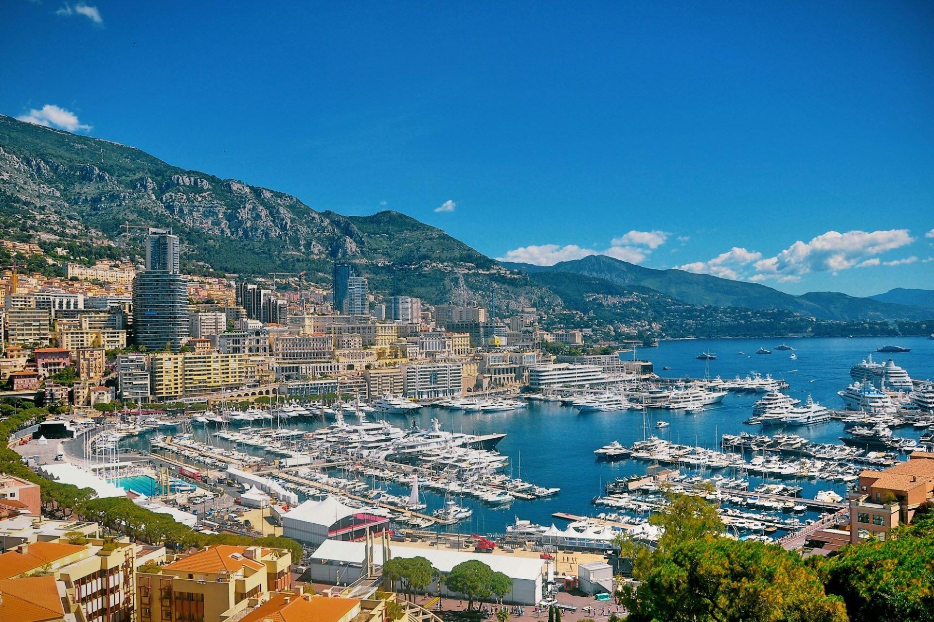 Harbour with yachts, apartment buildings, mountains, and blue sea