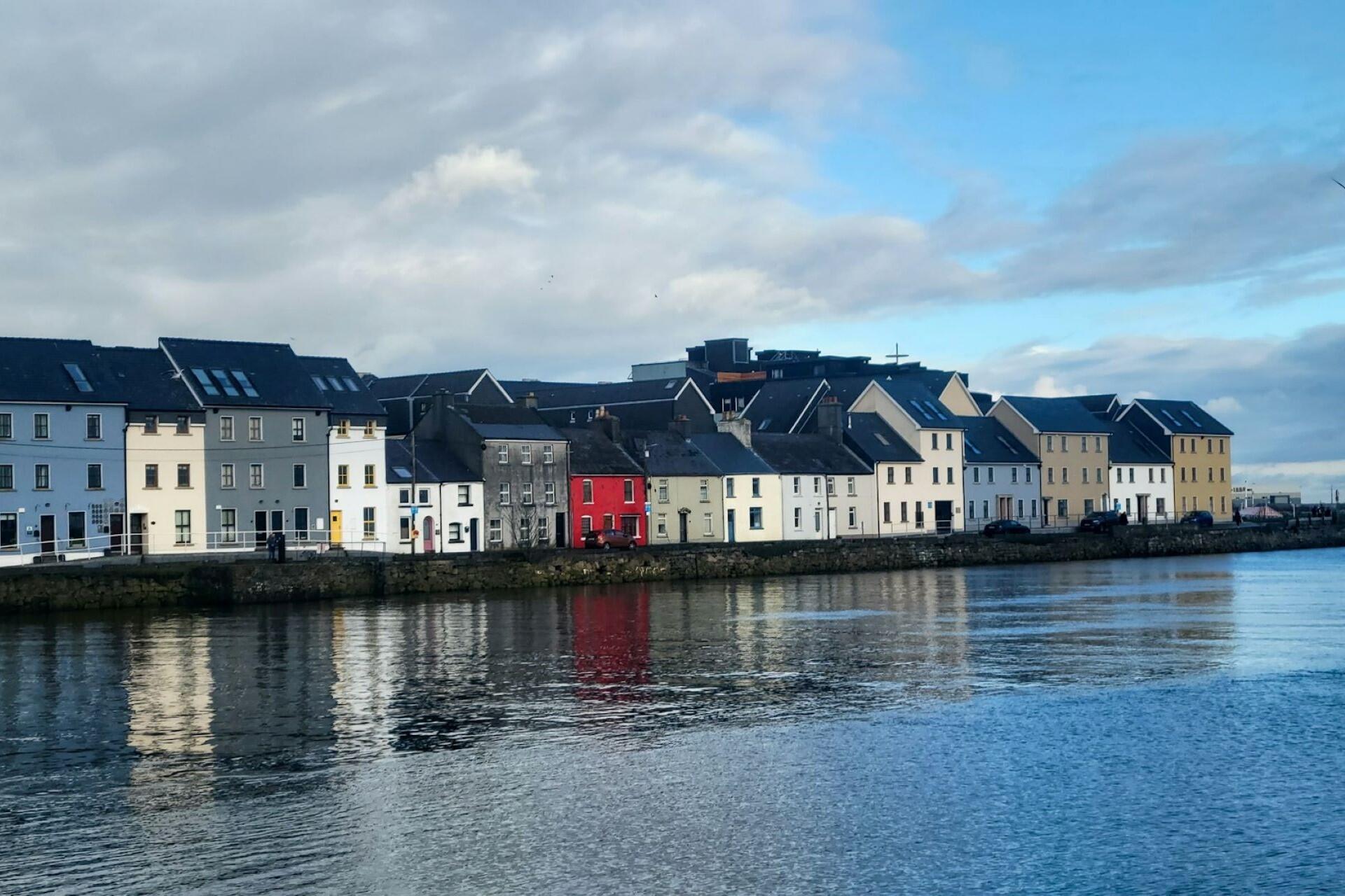 Row of colourful houses along a river with reflections in the water
