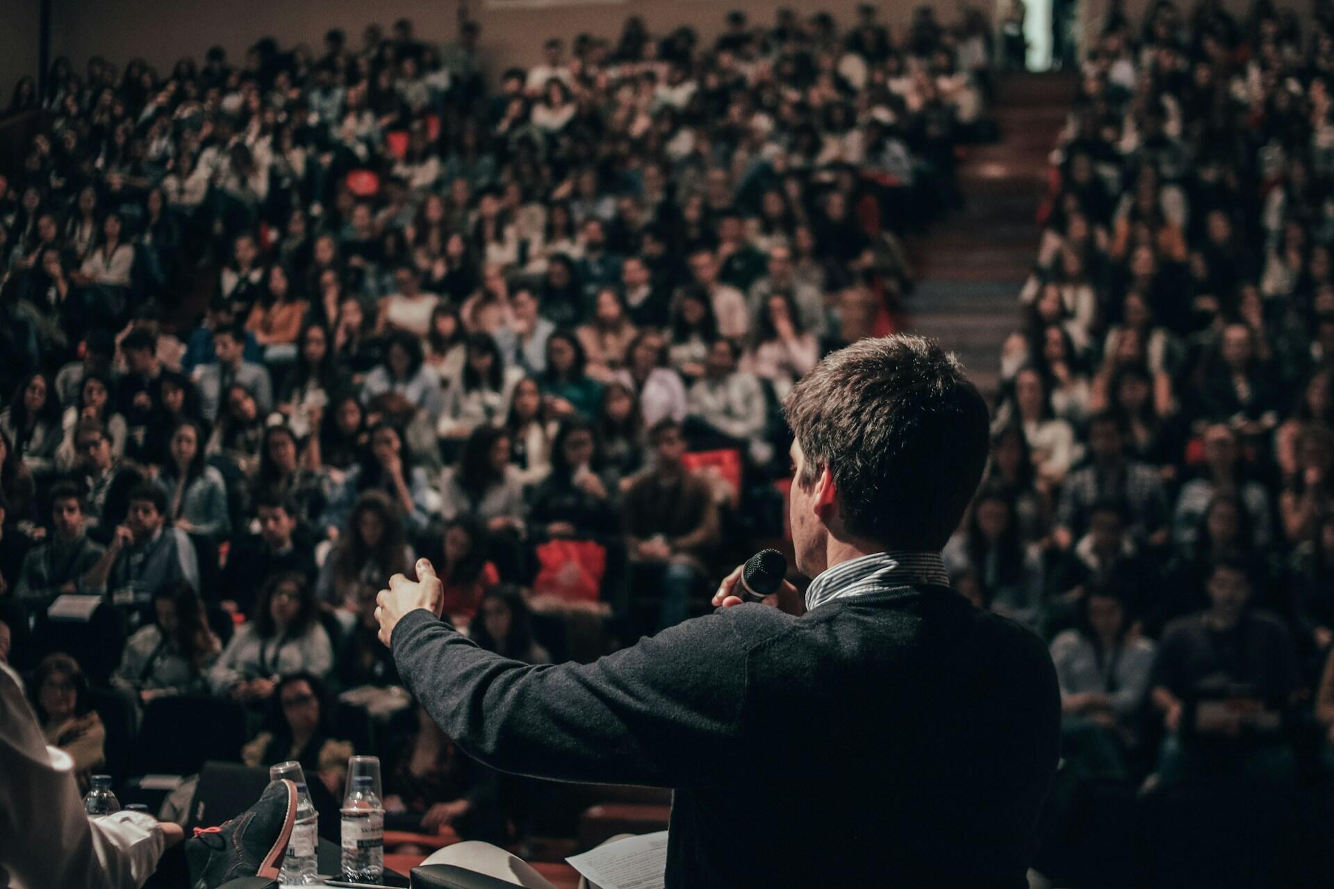 Speaker holding a microphone in front of a large audience