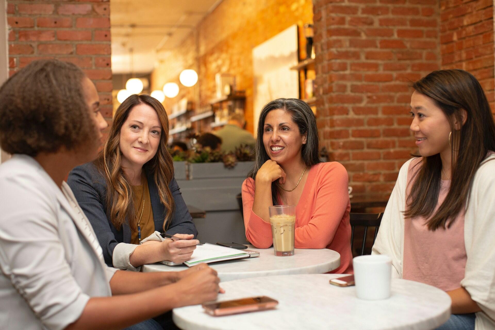 Four women talking around a table in a café