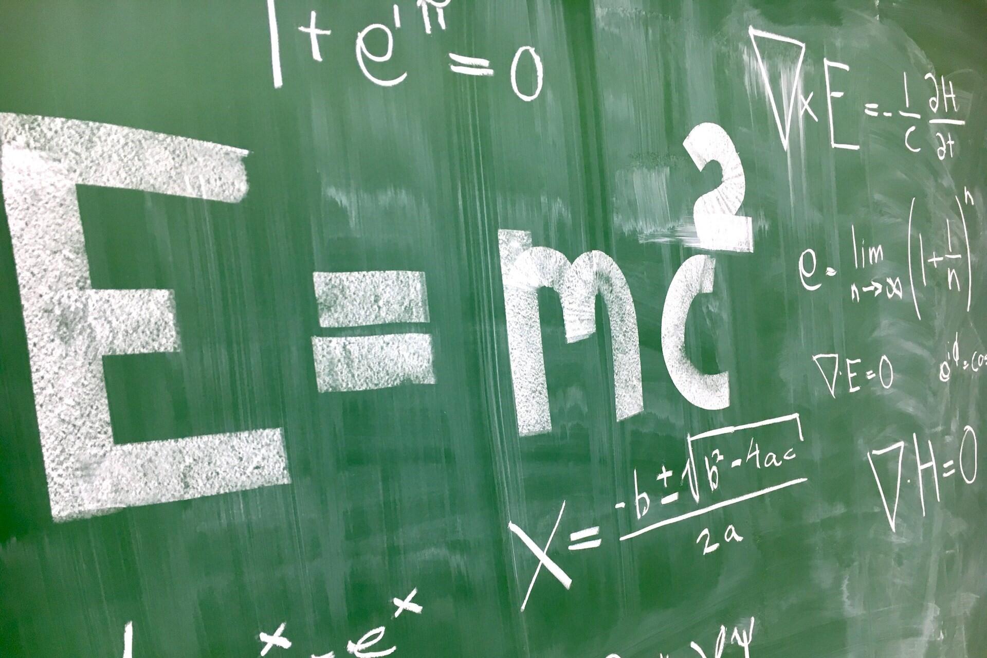 Mathematical equations written in chalk on a green chalkboard