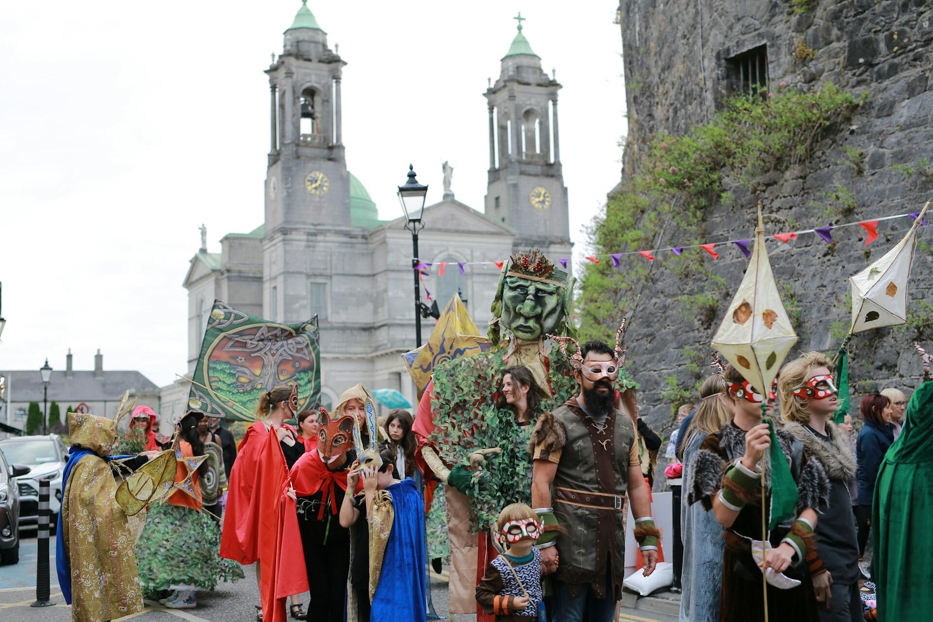Group of people wearing costumes and masks walking in a street parade