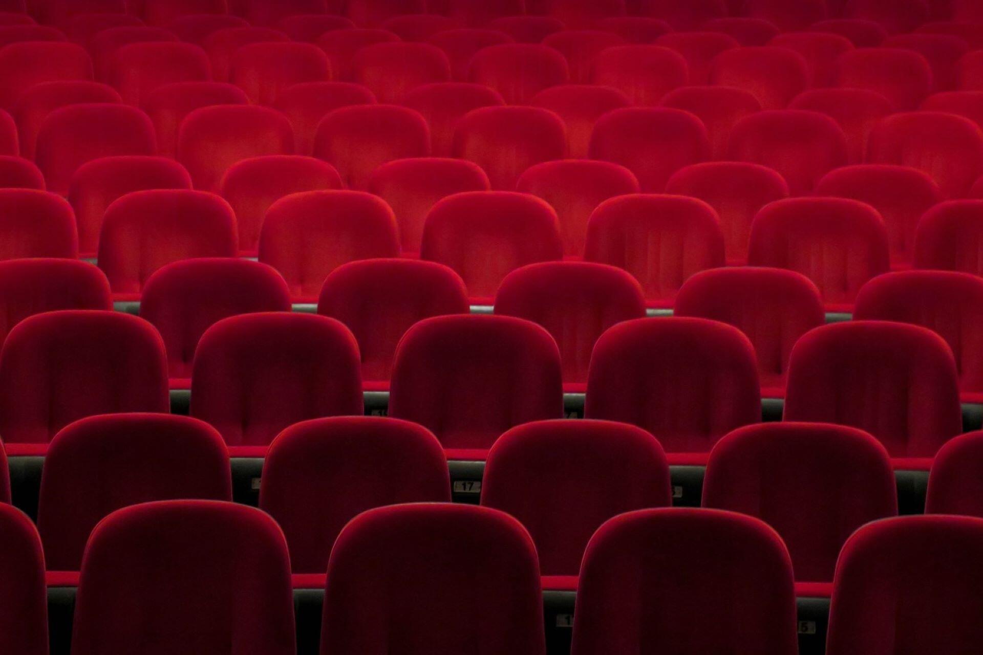 Rows of red cinema seats in an empty theatre