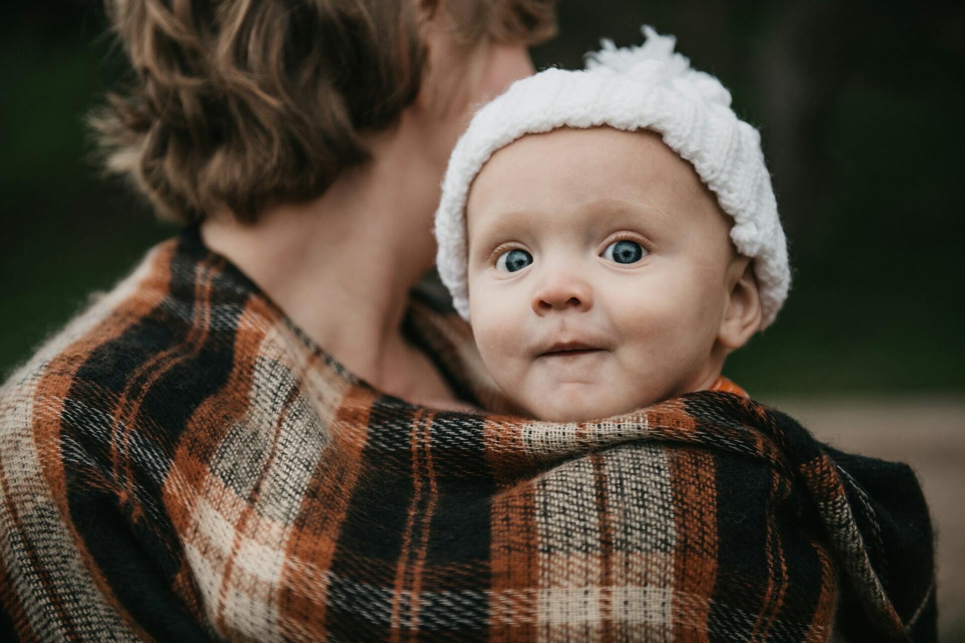 Baby wrapped in a blanket being held by a parent