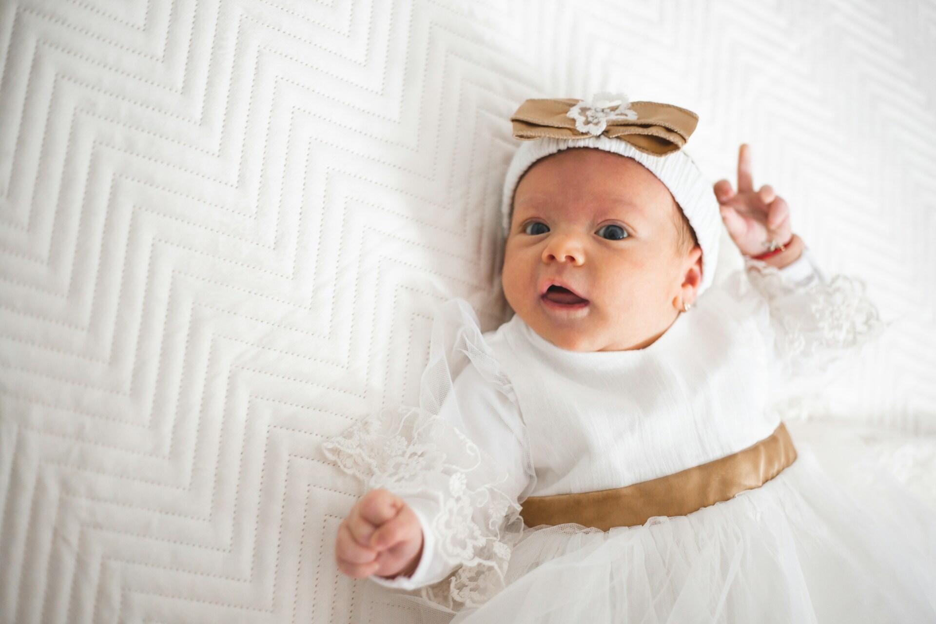 Baby wearing a white outfit lying on a textured blanket