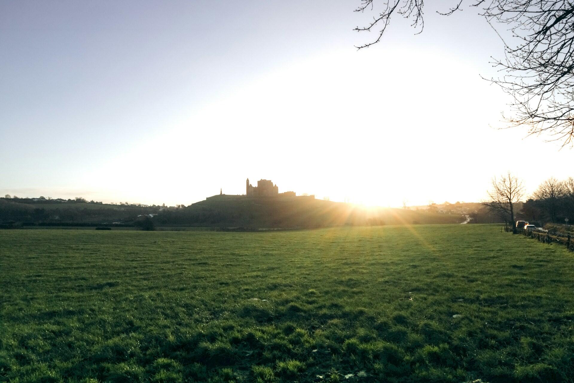 Castle silhouette on a hill at sunset with open fields