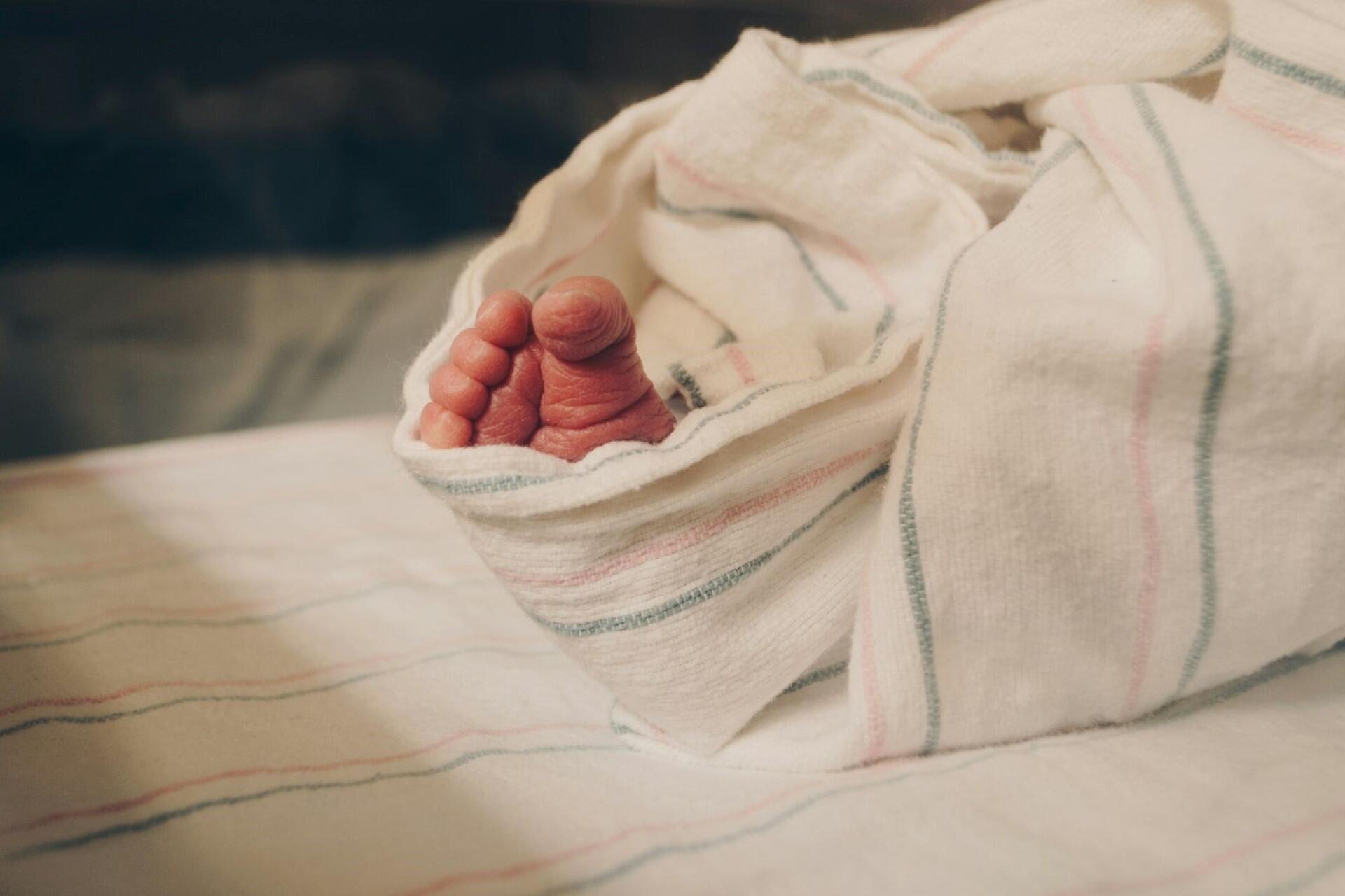 newborn baby feet wrapped in hospital blanket