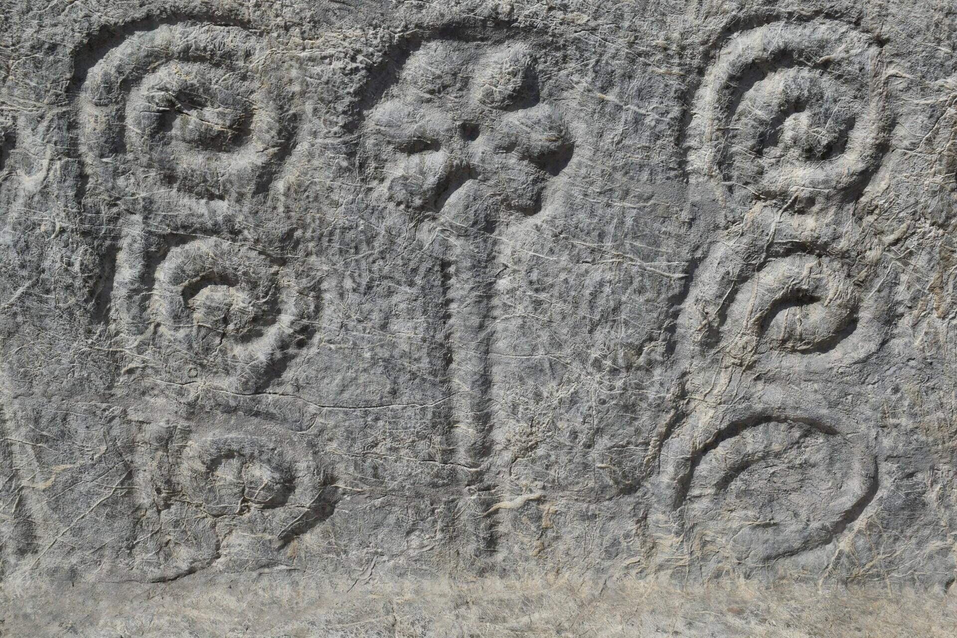 Ancient stone carving with spiral patterns and markings