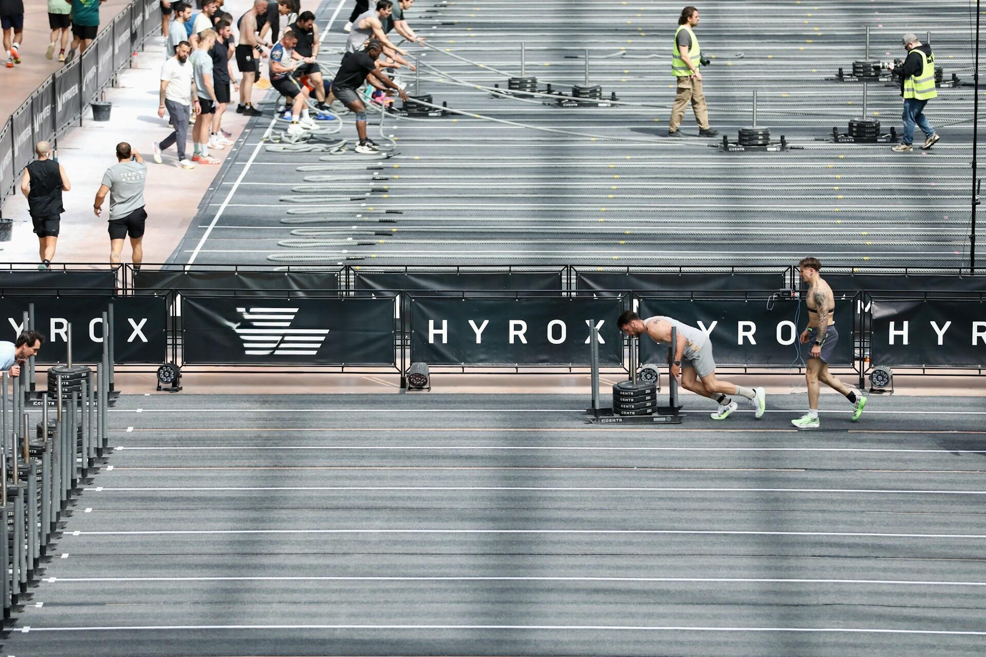athletes pulling sleds in parallel lanes during hyrox race