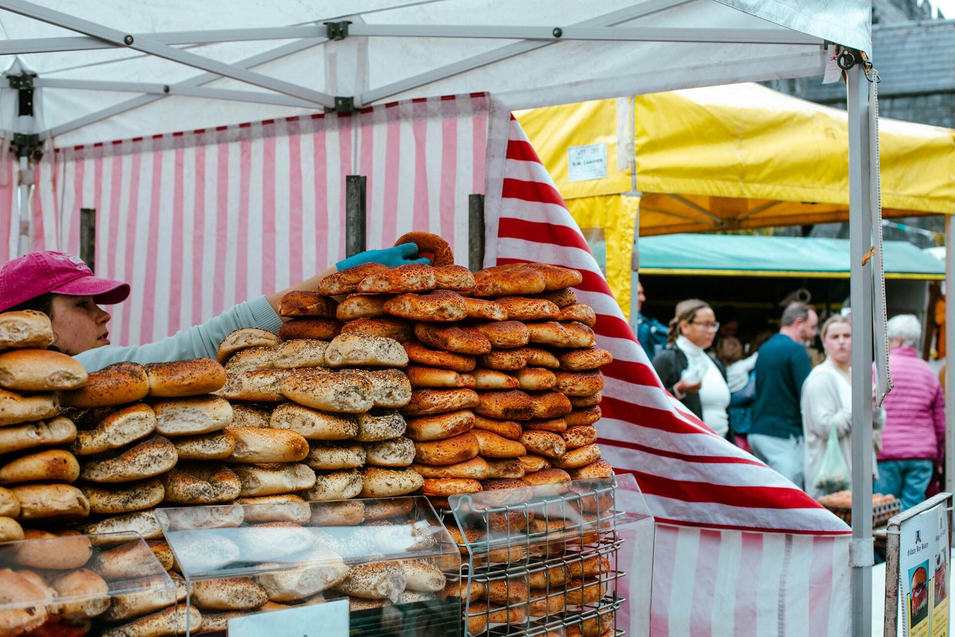Market stall with bread and people browsing at an outdoor fair