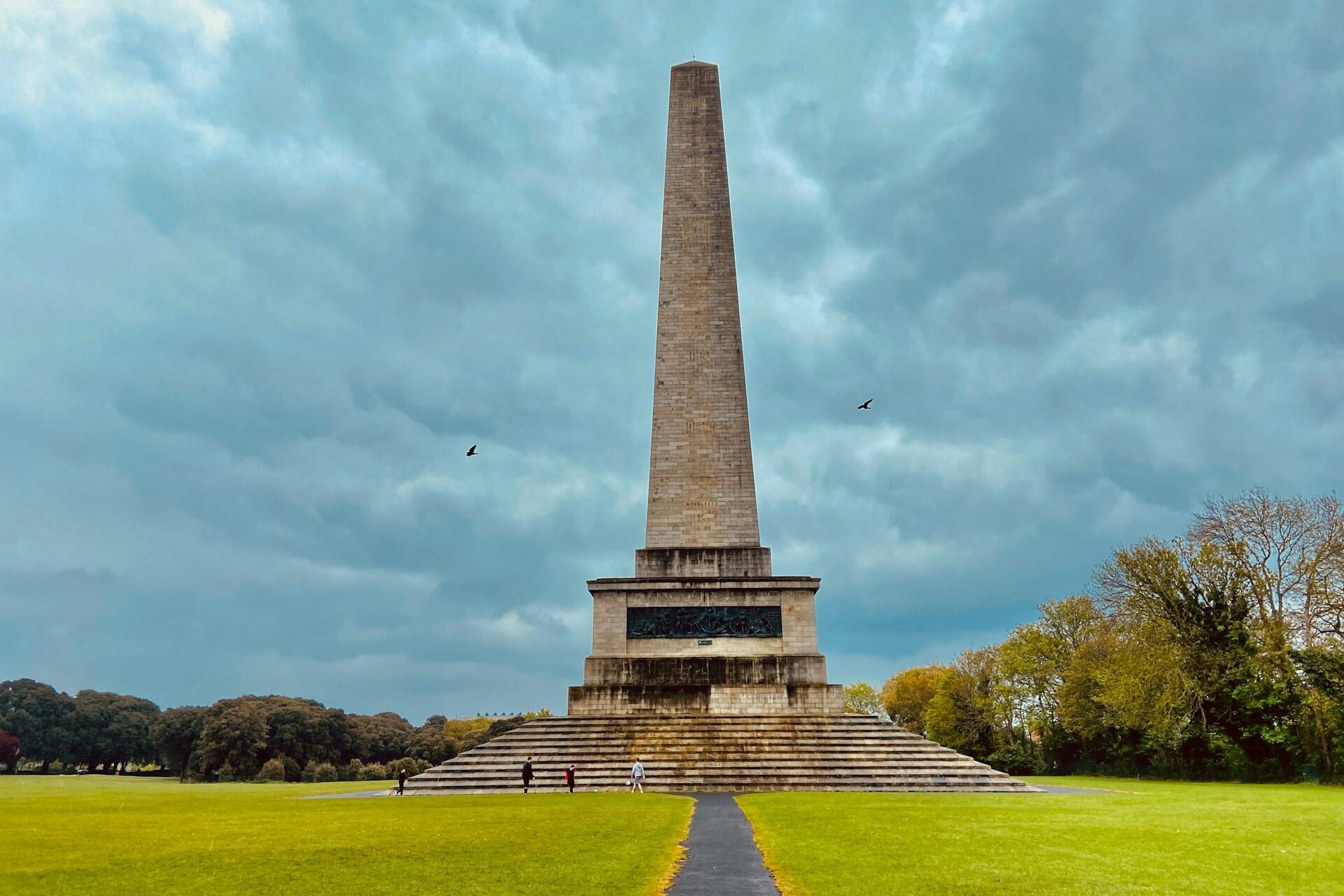 Wellington Monument obelisk in Phoenix Park Dublin with green lawns and cloudy sky