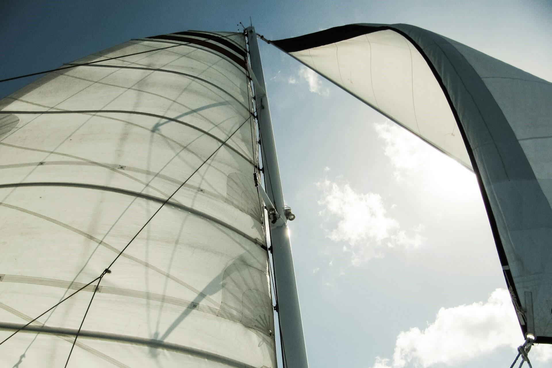 Large sailing ship sails filled with wind against the sky.