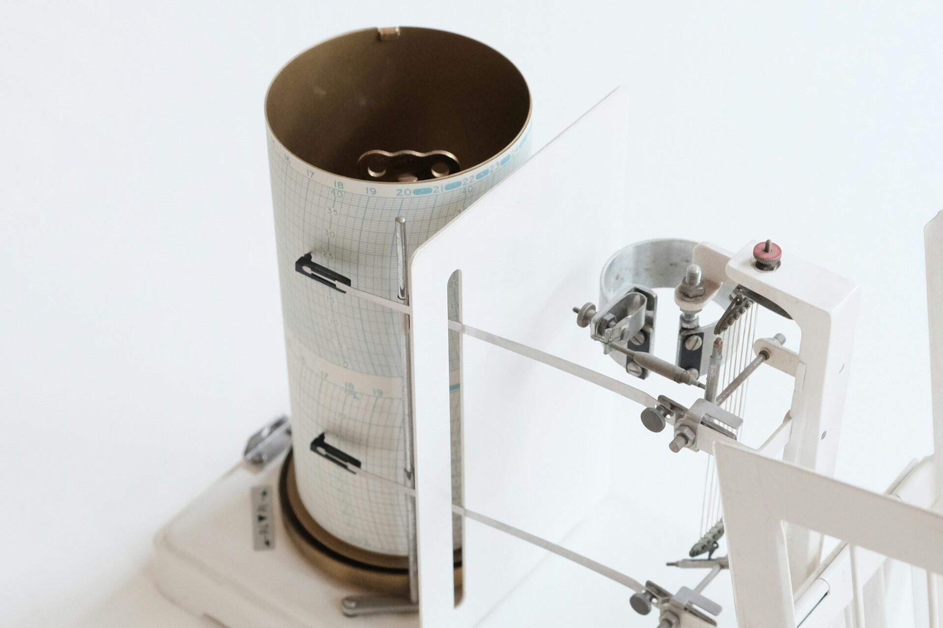 Scientific seismograph instrument recording ground vibrations on a rotating drum.