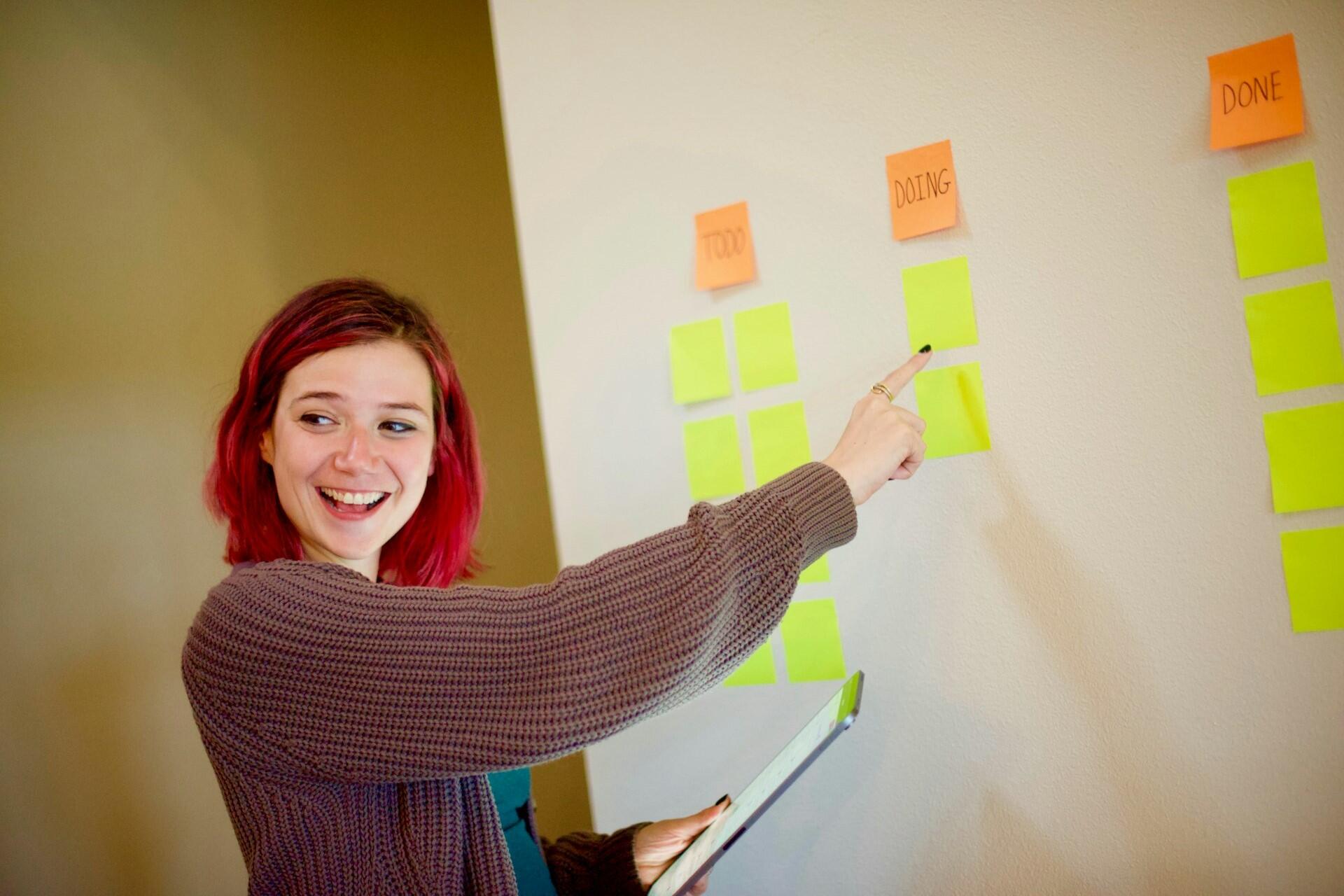 Teacher pointing at sticky notes while planning work on a wall