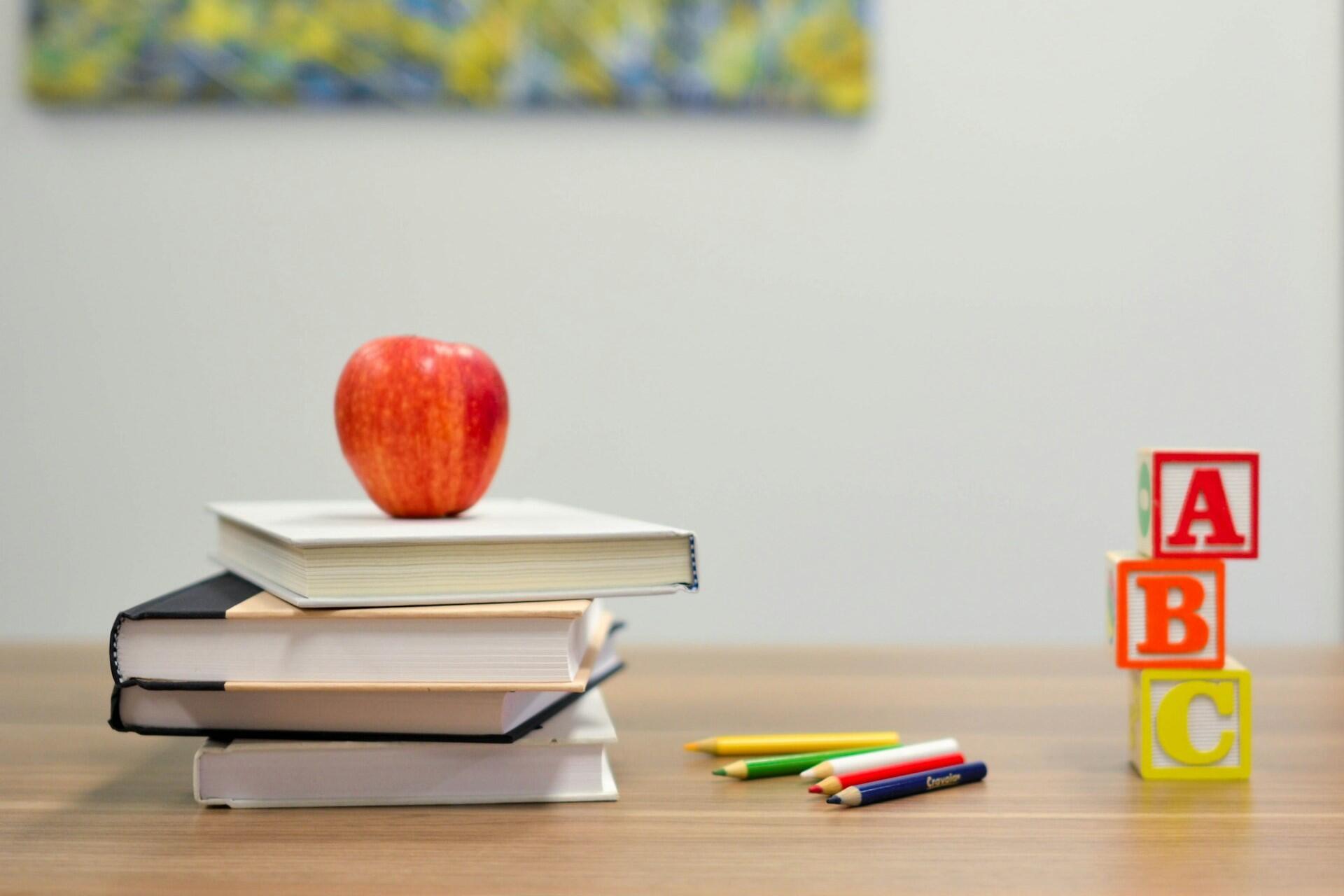 Books, pencils, apple and ABC blocks on a classroom desk