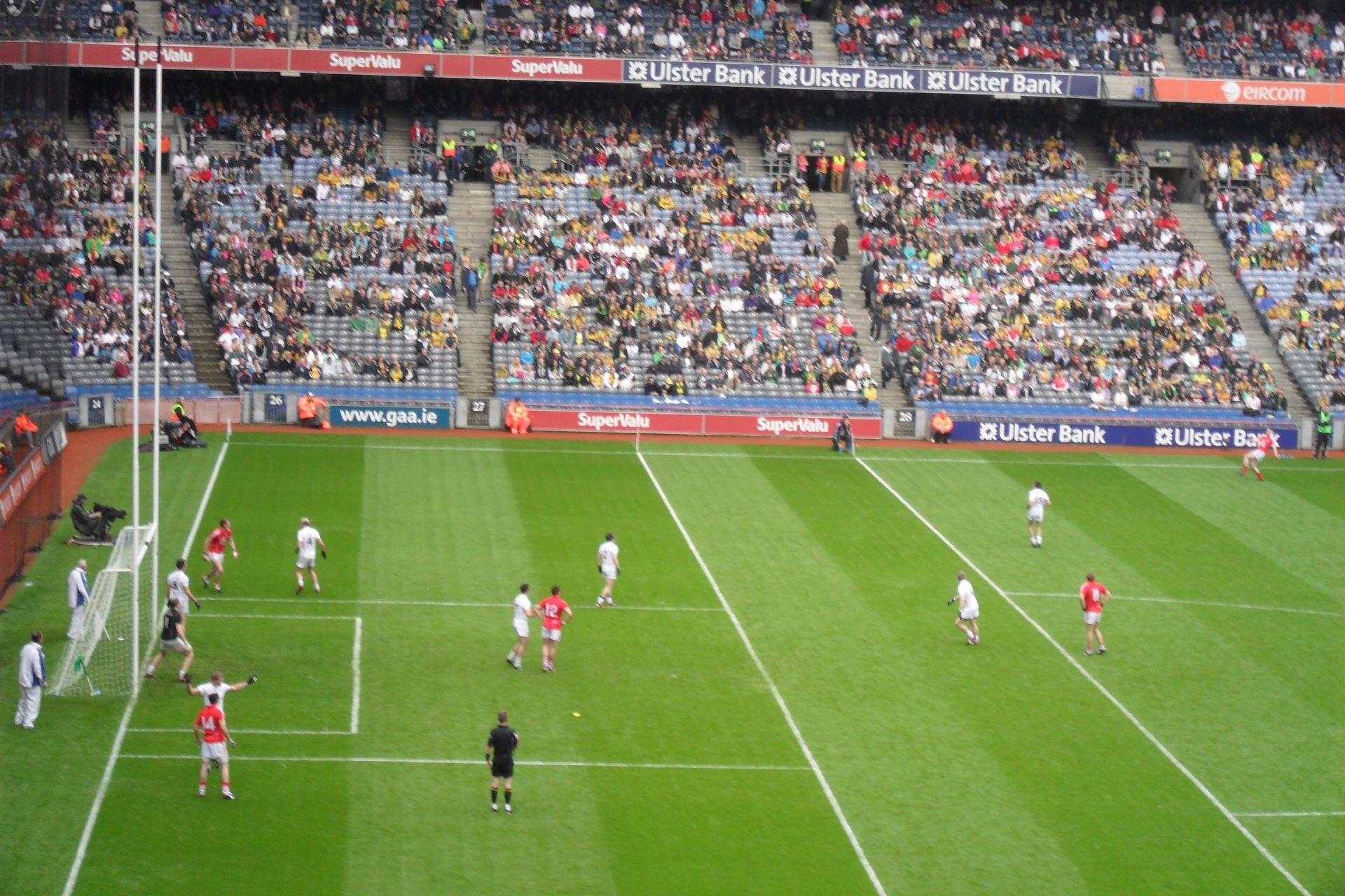 Gaelic football match near the goalposts on a marked stadium pitch with spectators in the stands
