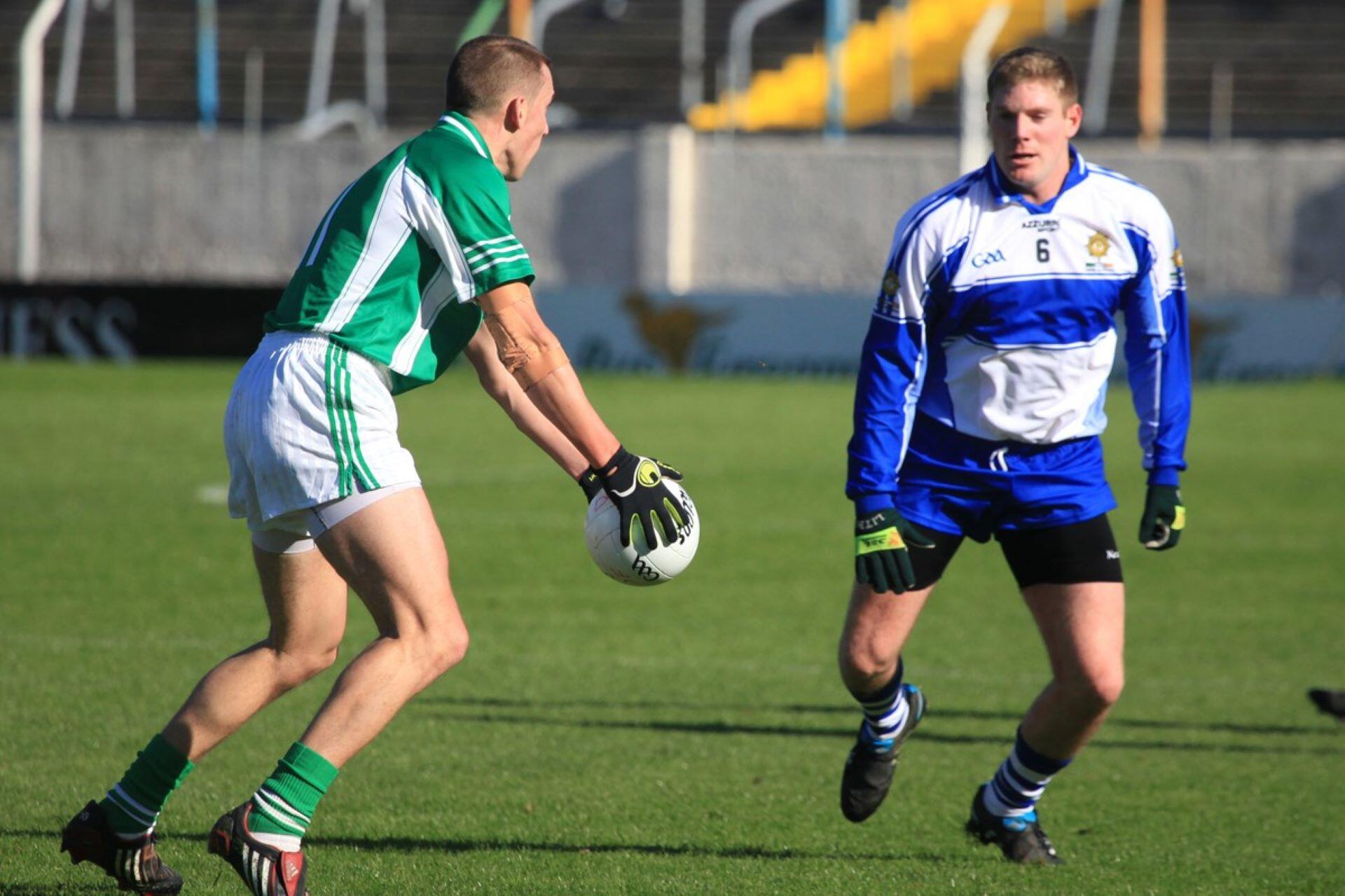 Gaelic football player holding the ball while facing a defender