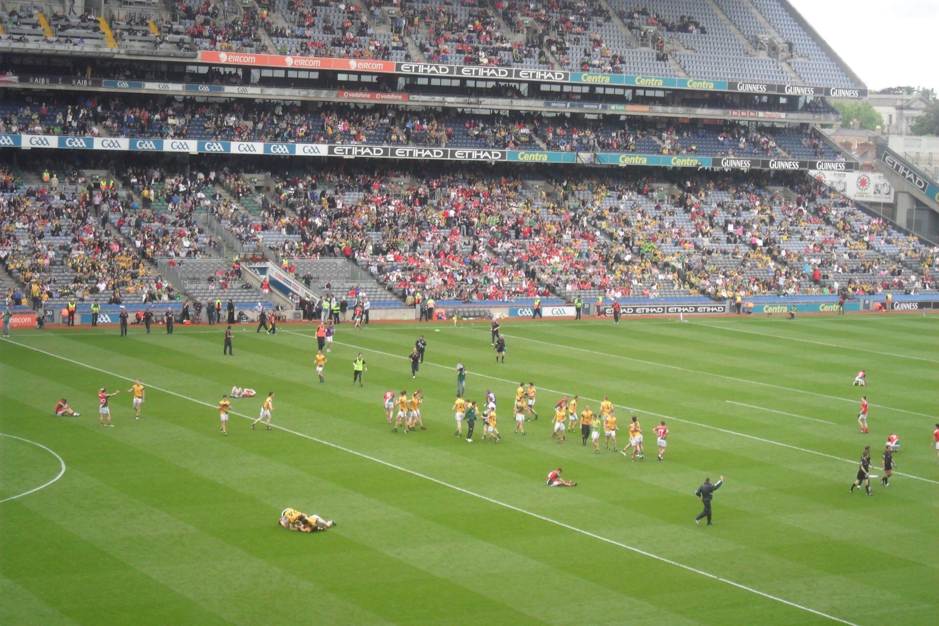Gaelic football players and spectators across a large stadium pitch