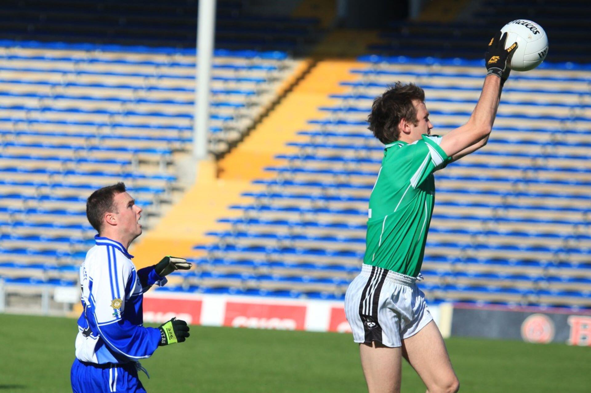 Gaelic football player jumping to catch the ball above an opponent