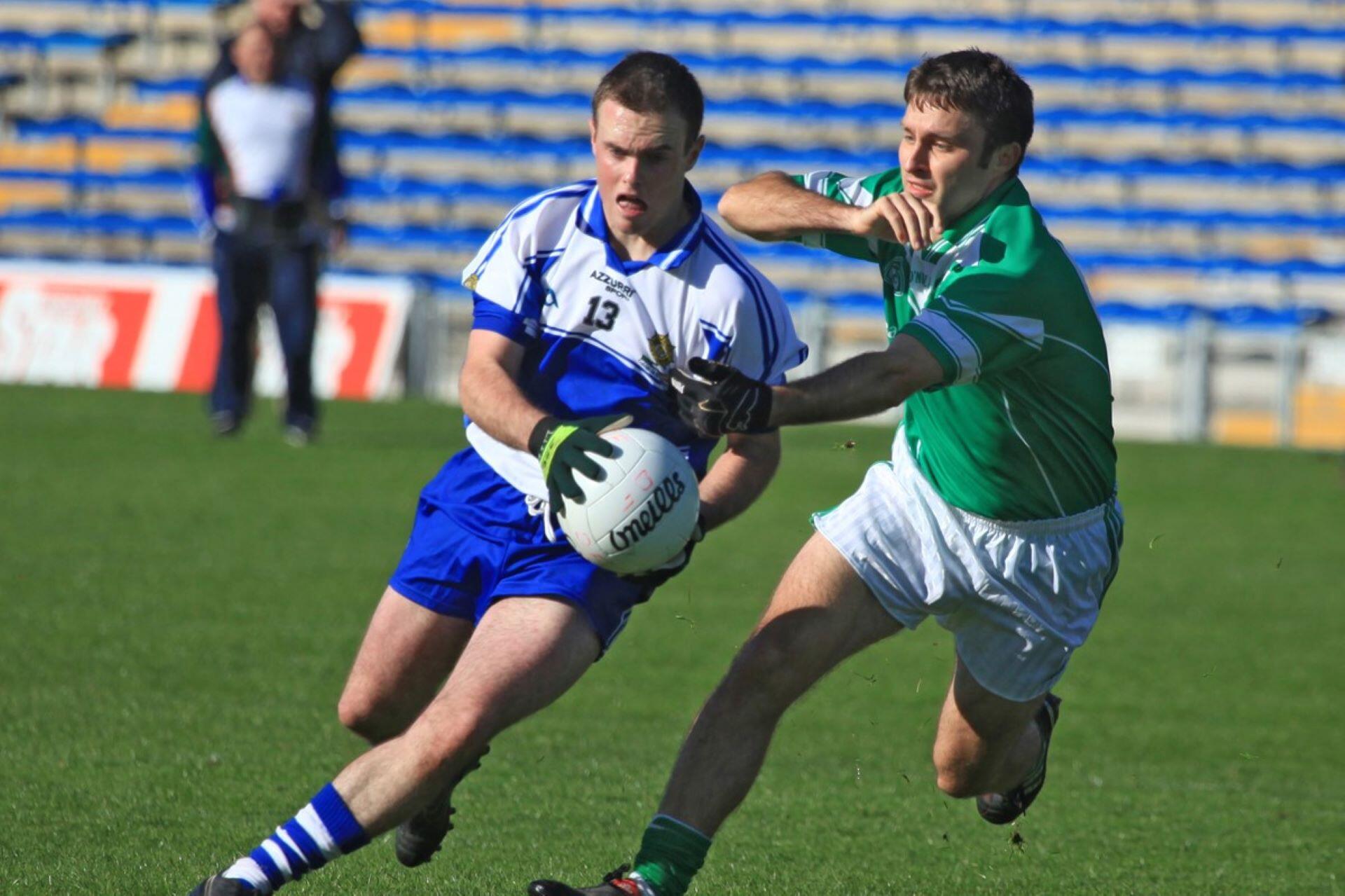 Gaelic football player carrying the ball while an opponent challenges him