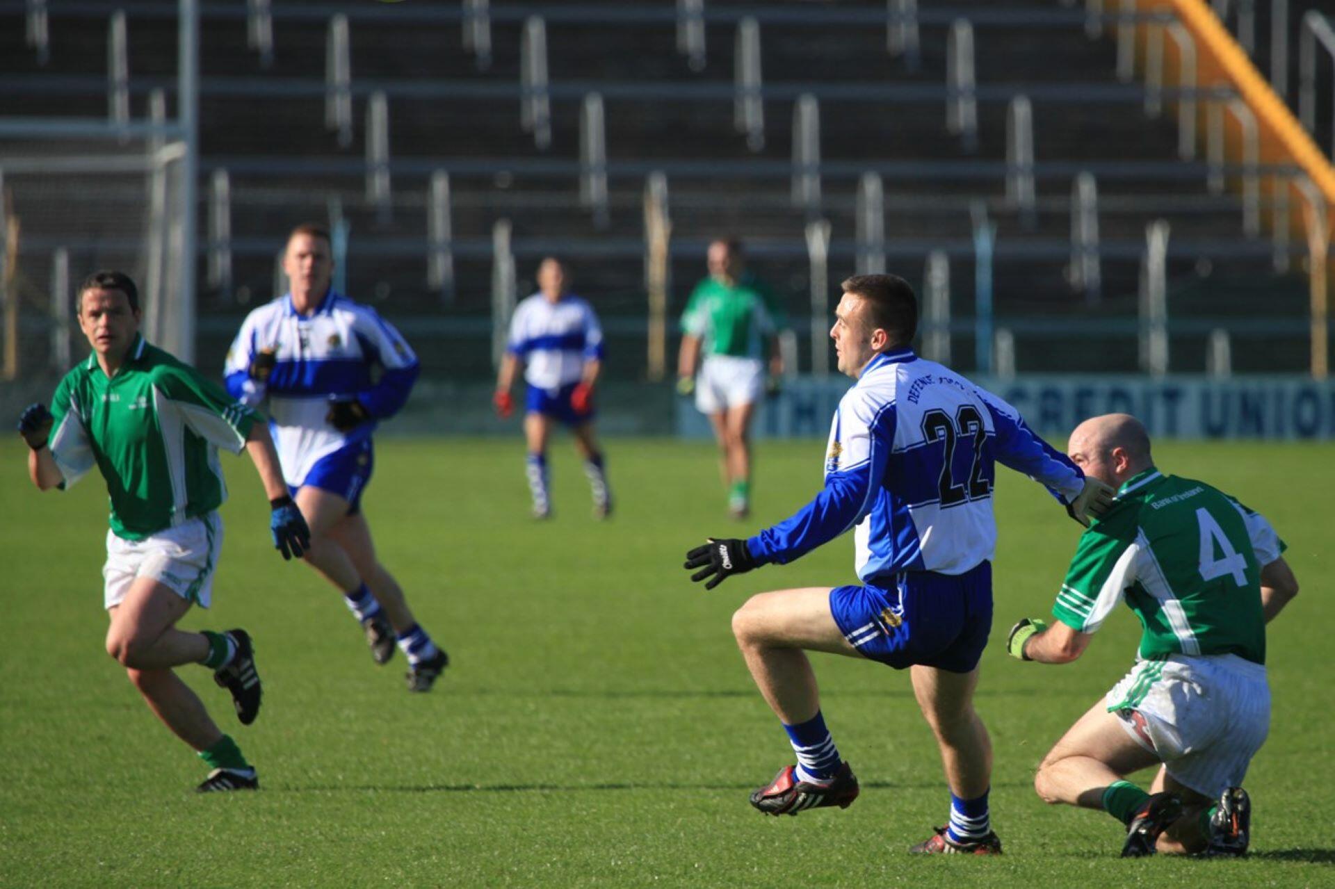 Gaelic football players in green and blue-white kits contesting possession