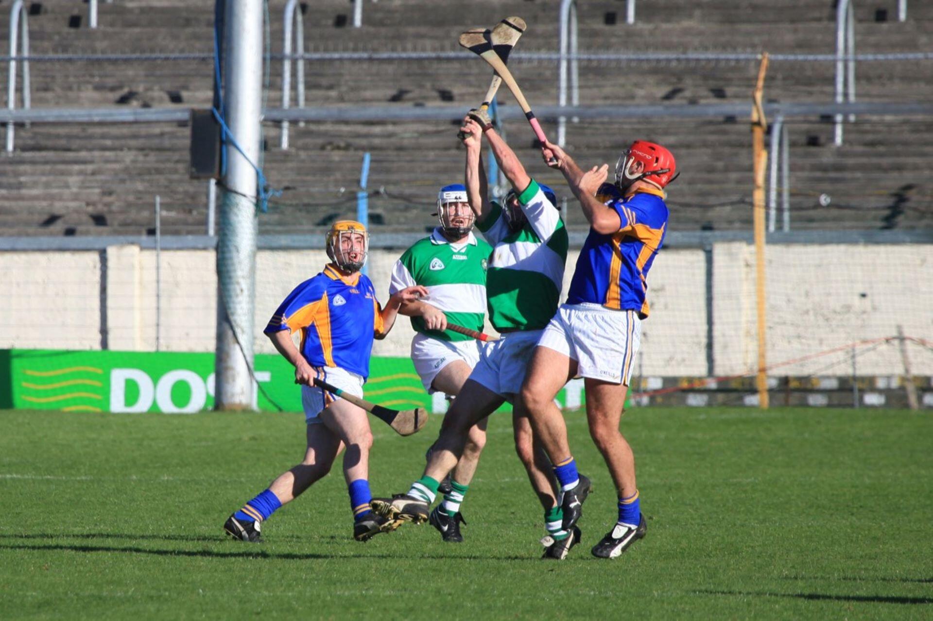 Hurling players raising their hurleys during an aerial contest for the sliotar
