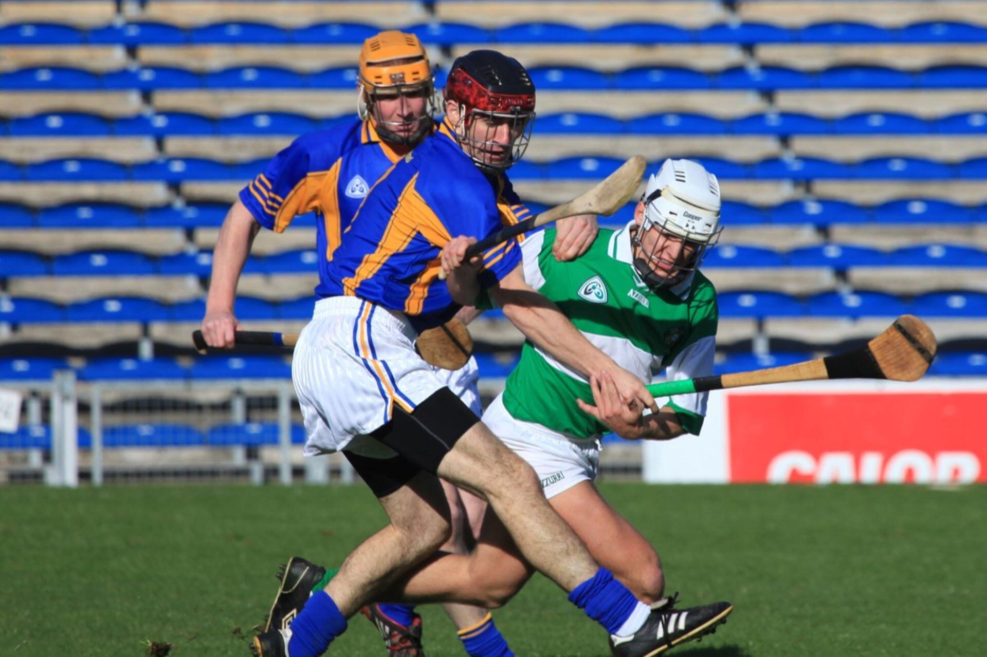 Three hurling players competing physically for possession during a match