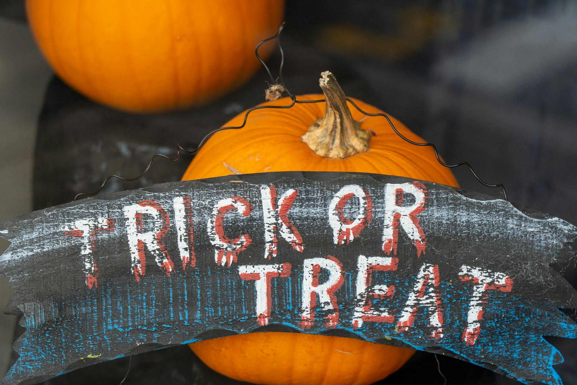 Trick or treat sign displayed in front of an orange pumpkin