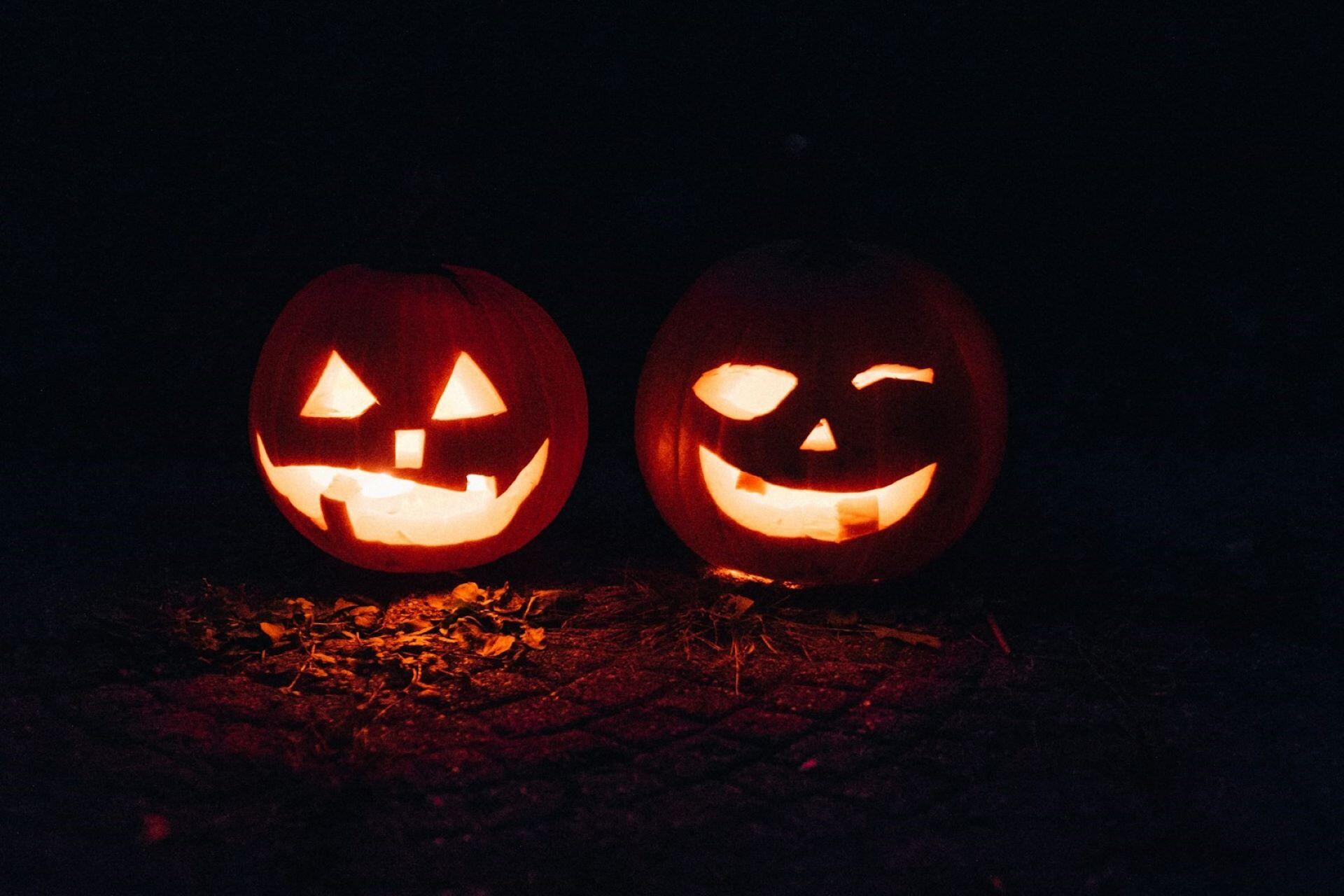 Two carved pumpkins glowing in the dark