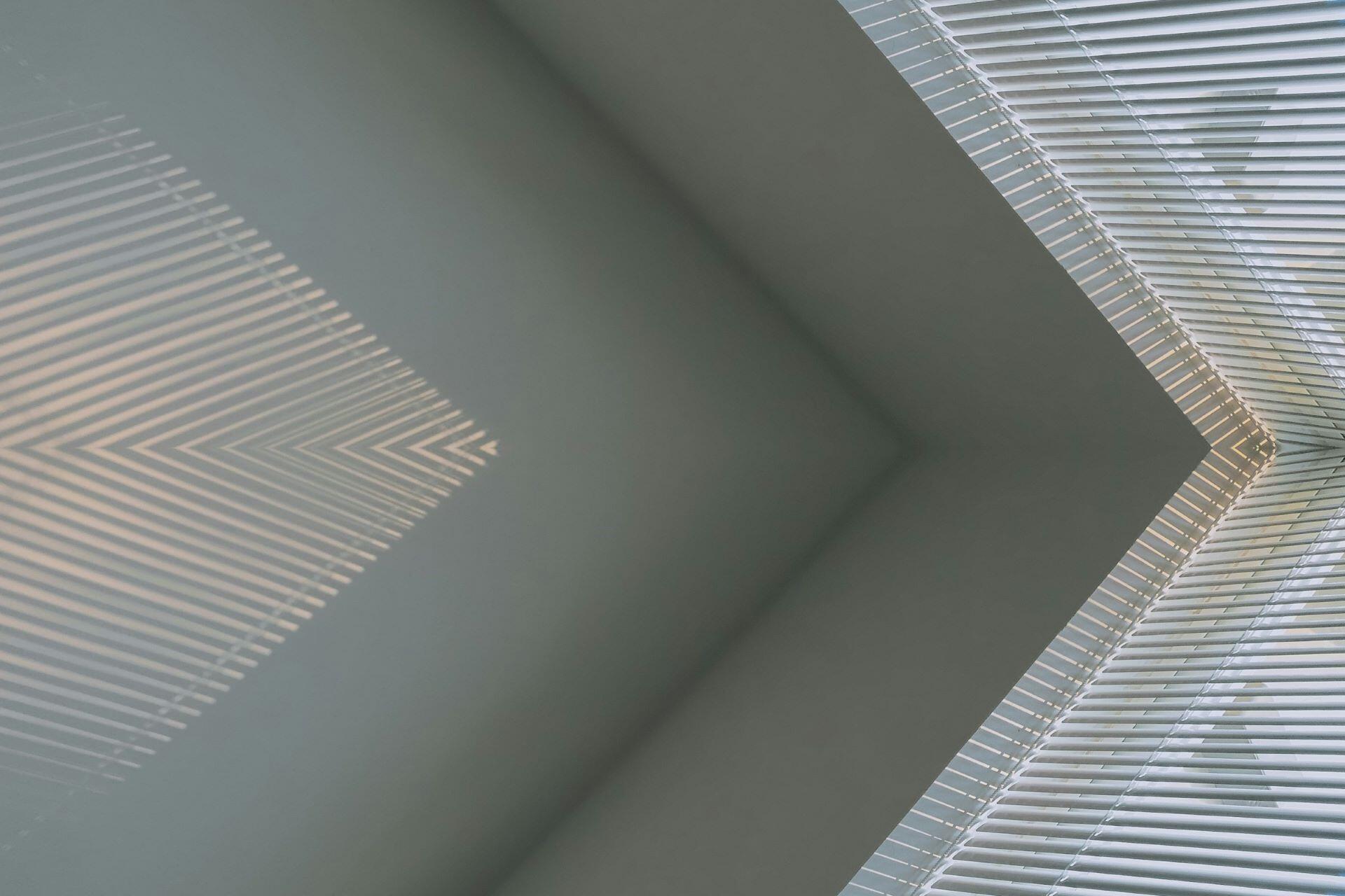 Geometric shadows from window blinds falling across a wall