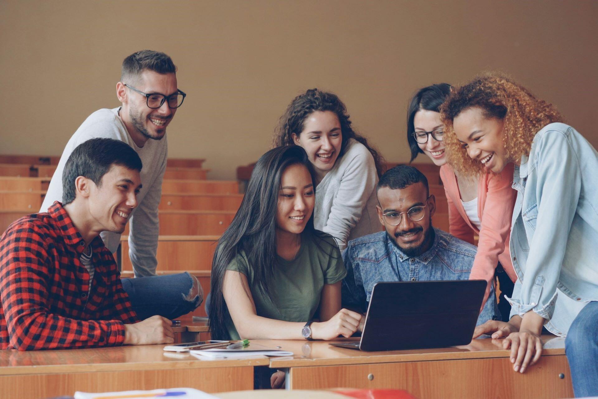 Students gathered around a laptop in a classroom