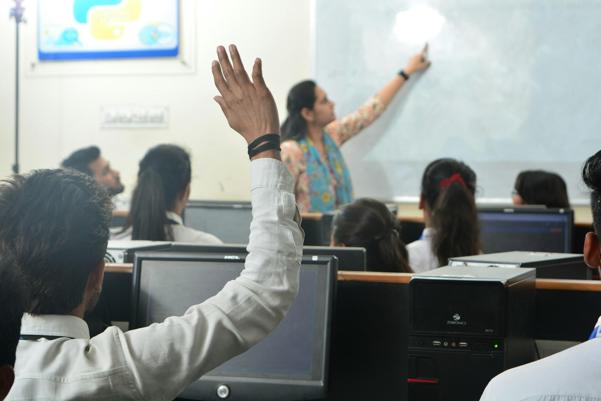 Student raising a hand in a computer classroom