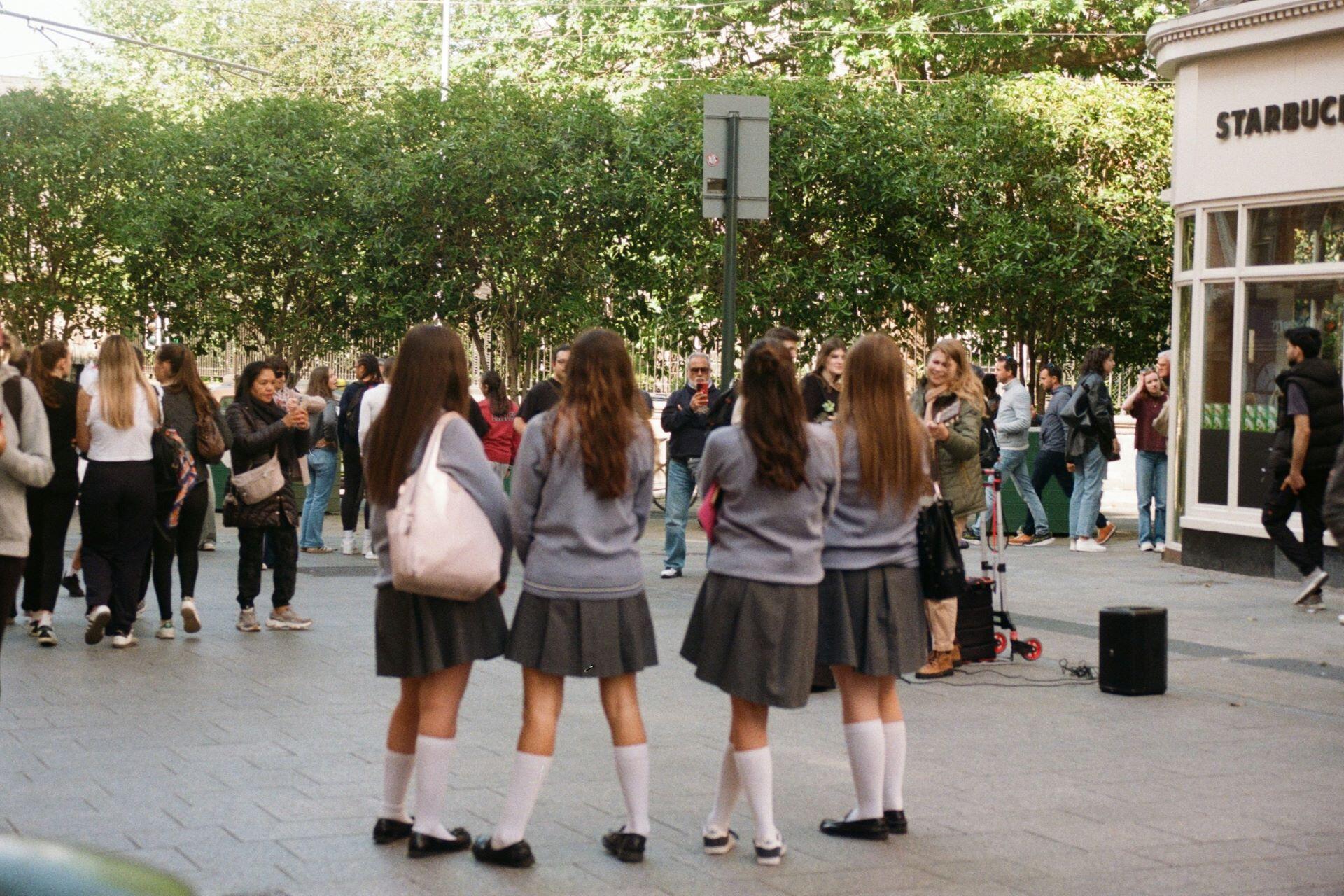 Four students in school uniforms standing together outdoors