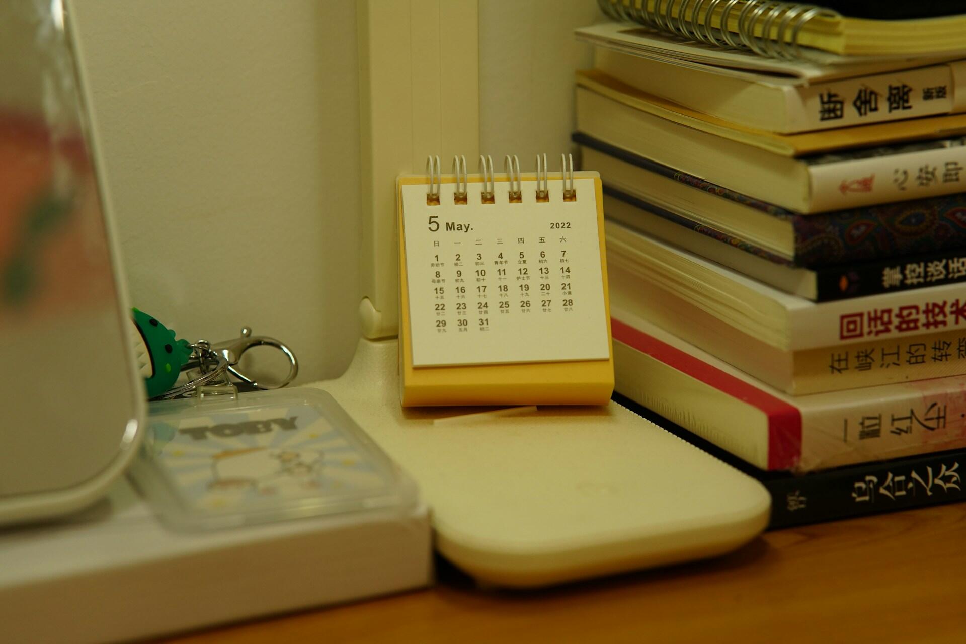 Small desk calendar beside a stack of books and notebooks