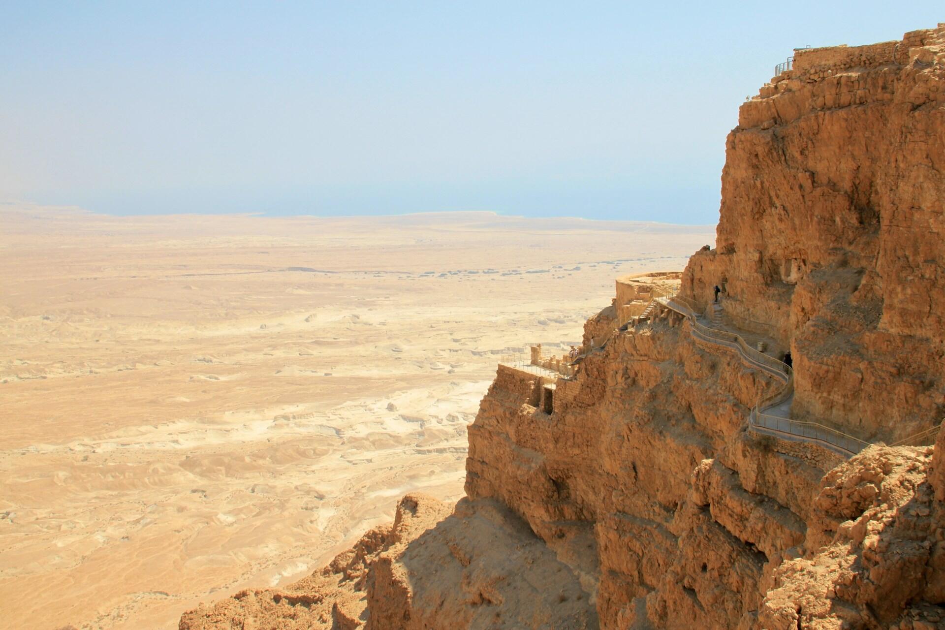 צוקי מדבר סלעיים עם שביל מתפתל המשקיף על נוף עצום וצחיח תחת שמיים כחולים וצלולים