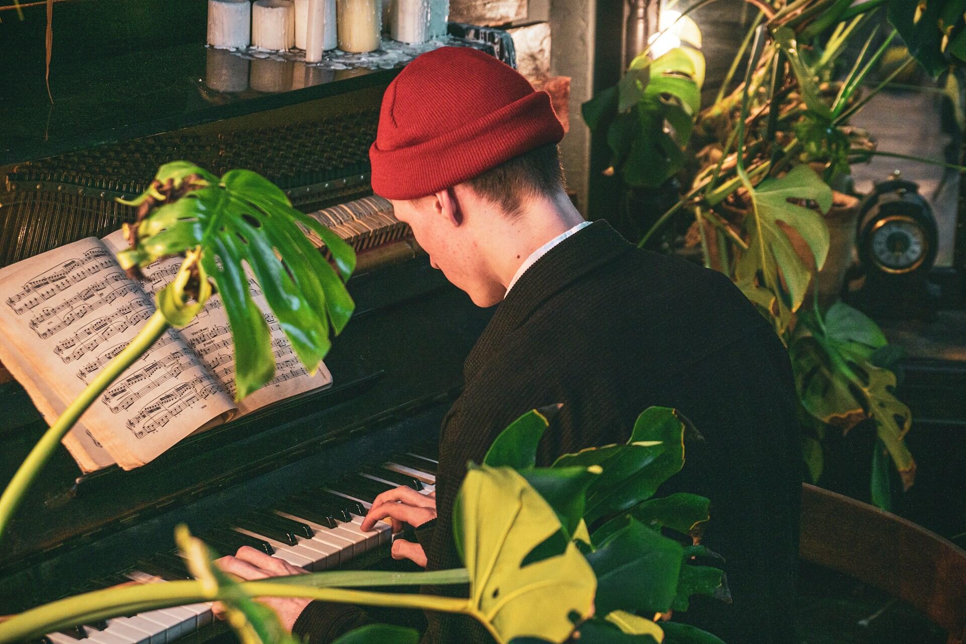 אדם צעיר מנגן על פסנתר סביב עציצים