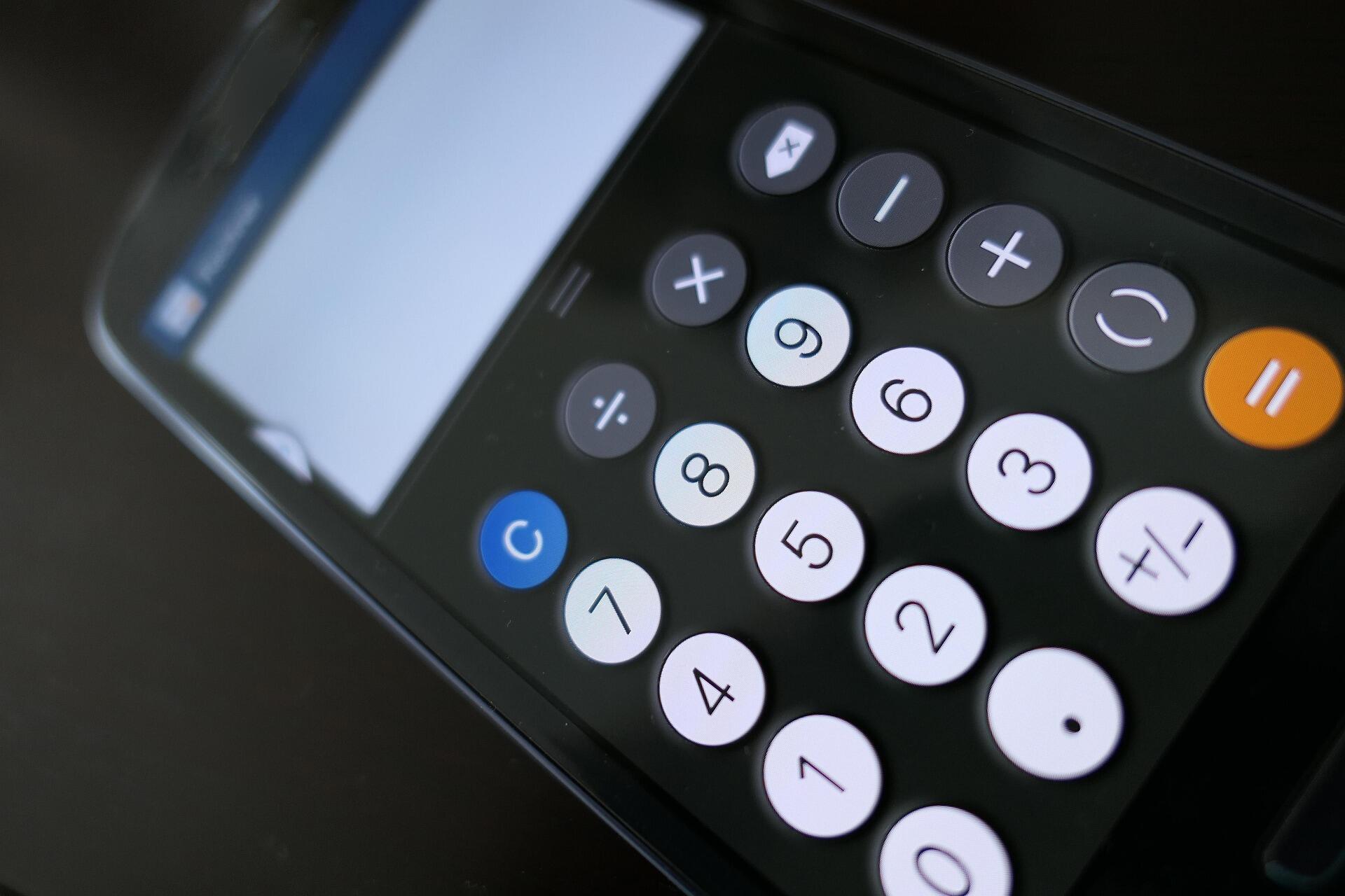 מסך סמארטפון המציג אפליקציית מחשבון עם לחצני מספרים ופונקציות על משטח כהה