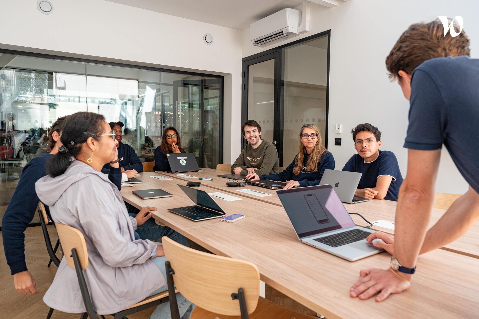 חברי צוות מתאספים סביב שולחן ישיבות עם מחשבים ניידים במהלך פגישה בחלל משרדי מודרני