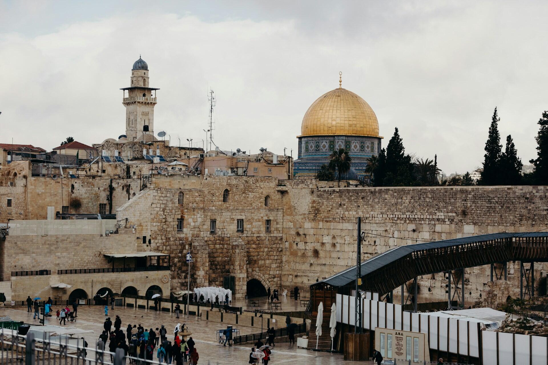 נוף של רחבת הכותל המערבי וכיפת הסלע המוזהבת בירושלים ביום מעונן עם אנשים שהתאספו בכיכר