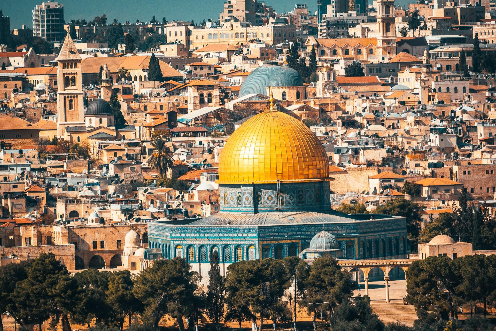 נוף של מסגד כיפת הסלע הזהוב מוקף בבניינים צפופים ועצים בירושלים