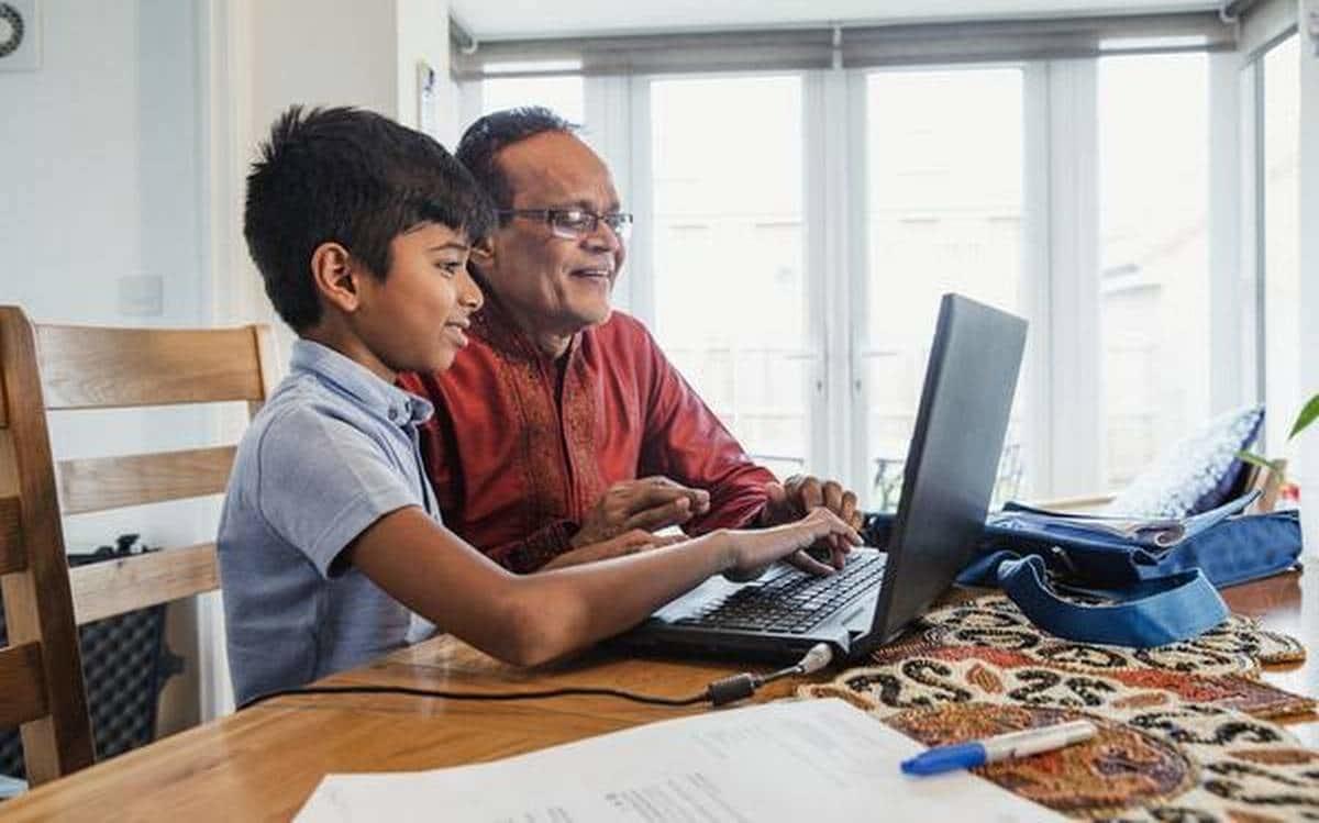 A father assisting his child with online learning