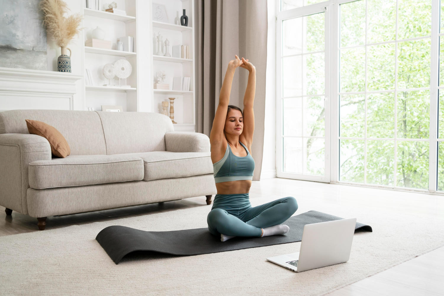 A yogi practising yoga at home with an online class on their laptop