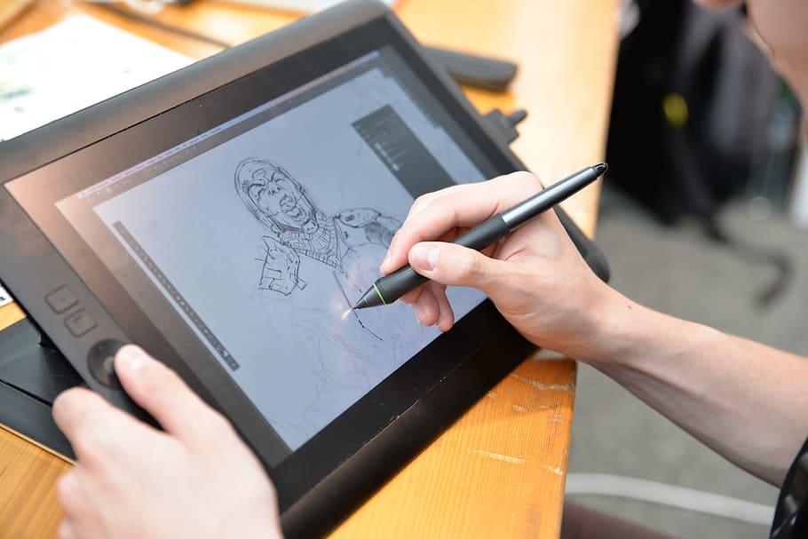 hand holding a pen and drawing on a tablet