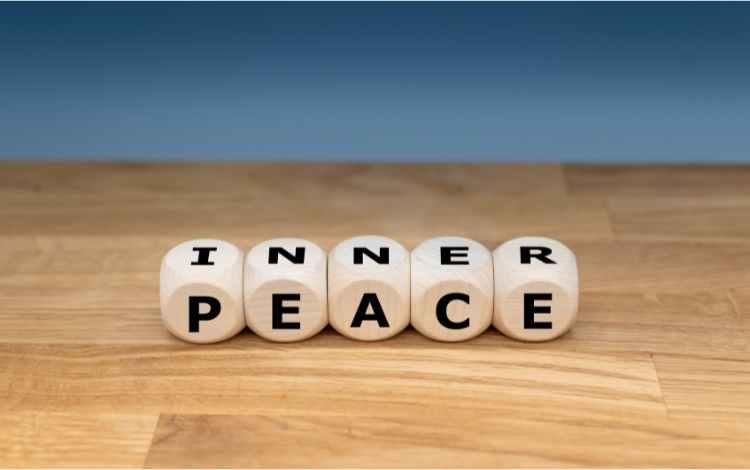 inner peace written on dice placed on a wooden platform against a light blue background
