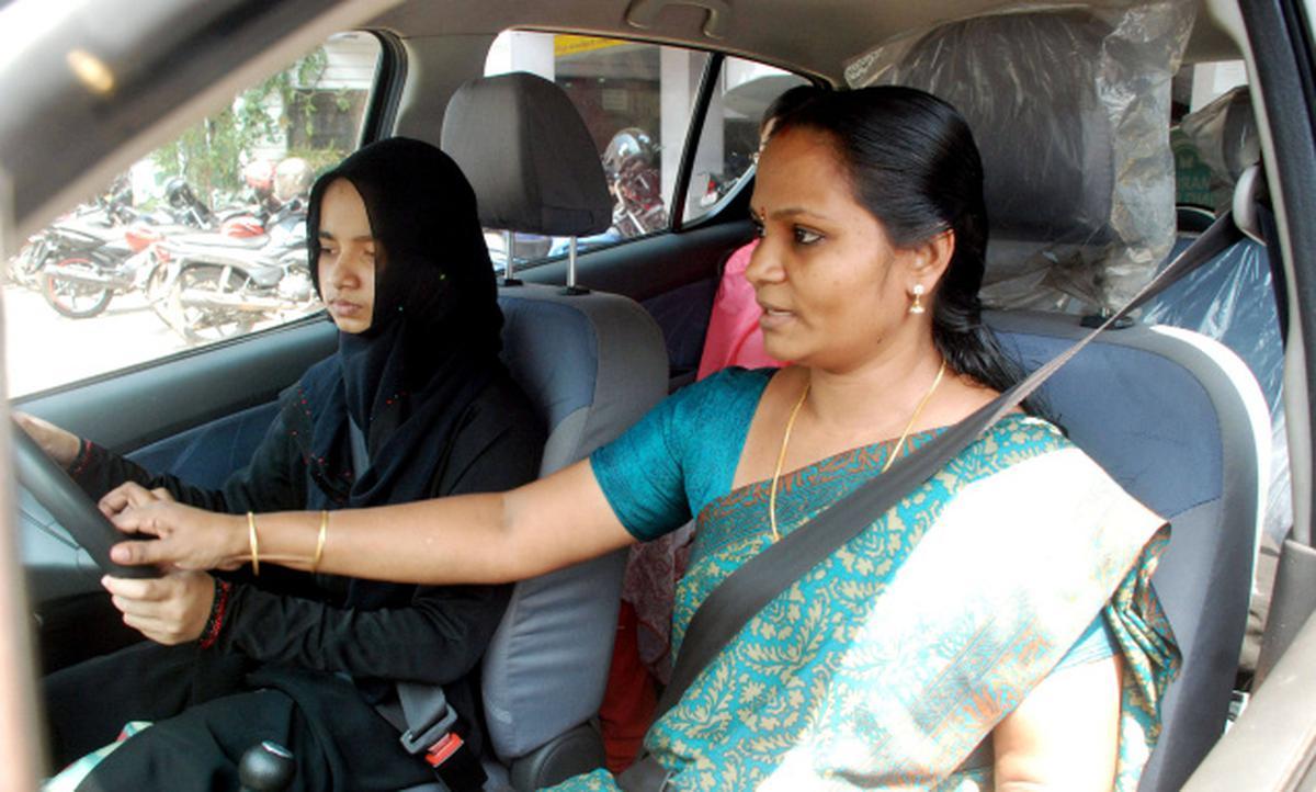 Female driving instructor teaching a young girl wearing burqa