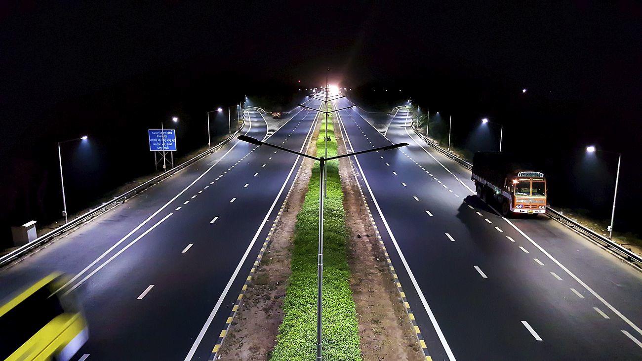 A relatively empty dual highway illuminated by artificial light at night.