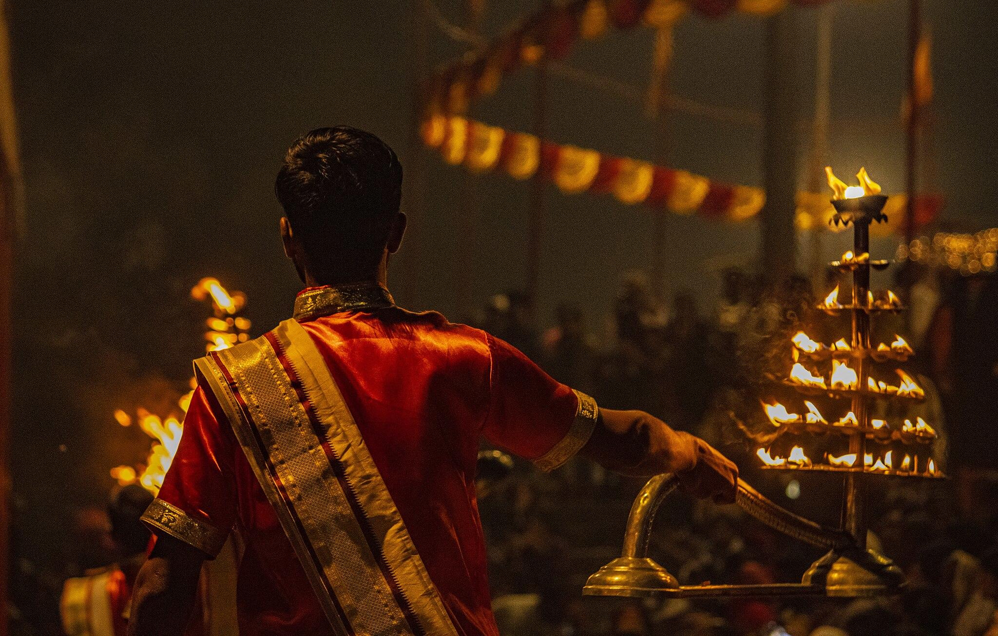 Ganga Aarti, a ceremony in the divinity of Goddess Ganga, at Varanasi among the three different cities where it is being performed—Haridwar, Rishikesh and Varanasi itself; a young Pandit holding the lamp of fire one fine evening in the banks of Ganga.