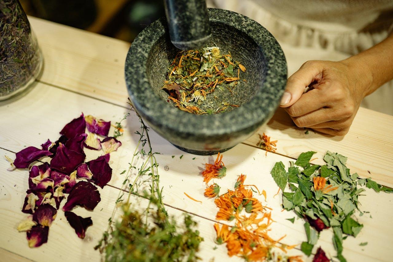 Dried herbs being processed in a mortar and pestle.