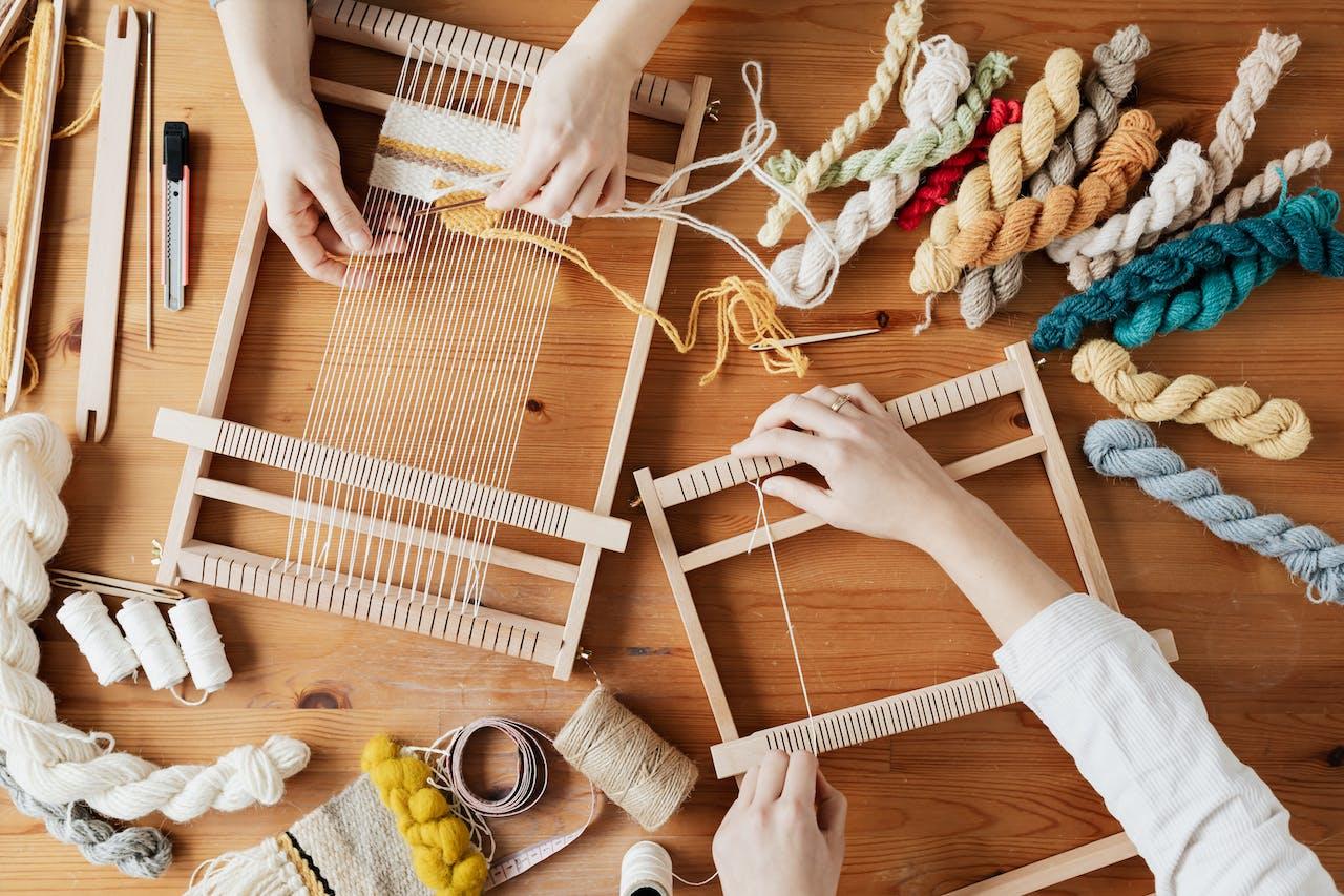 Two people weaving on a loom