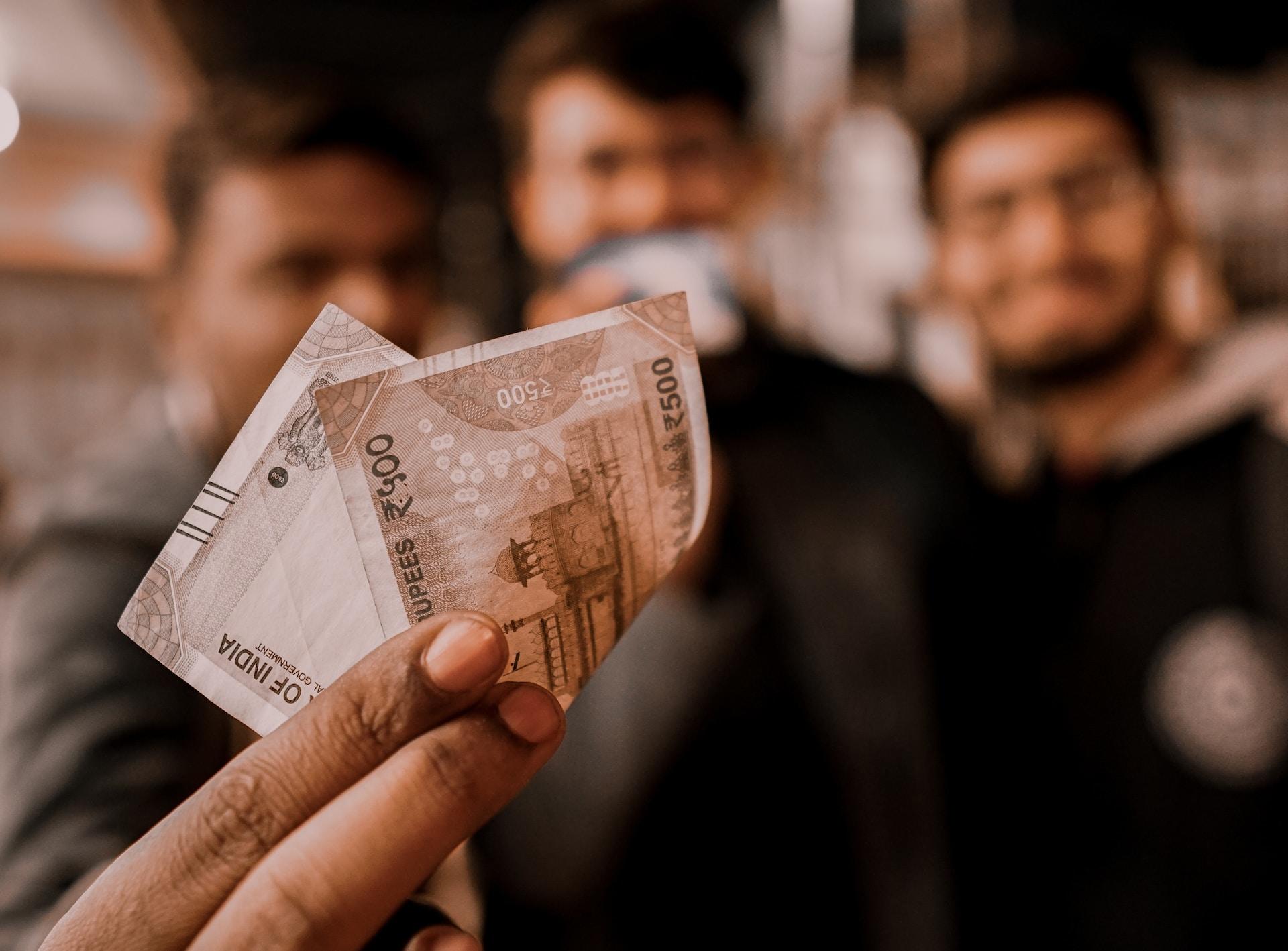 a person holding a 500 rupee note